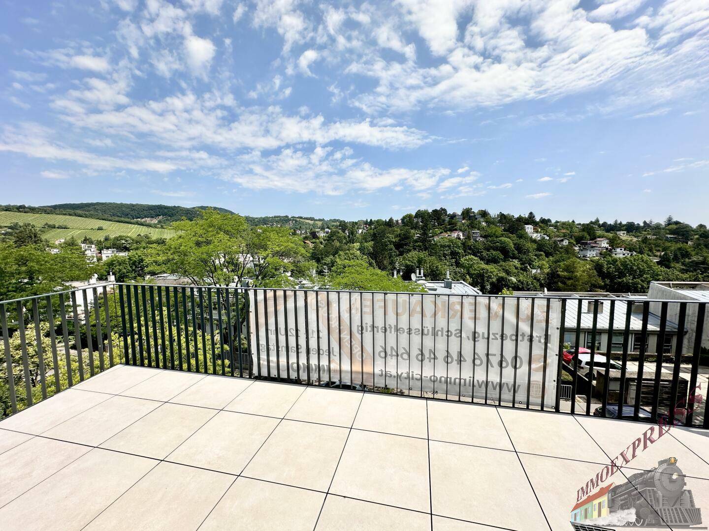 Sonniger Terrassenbereich mit Fliesenboden und weitem Blick in die Natur.