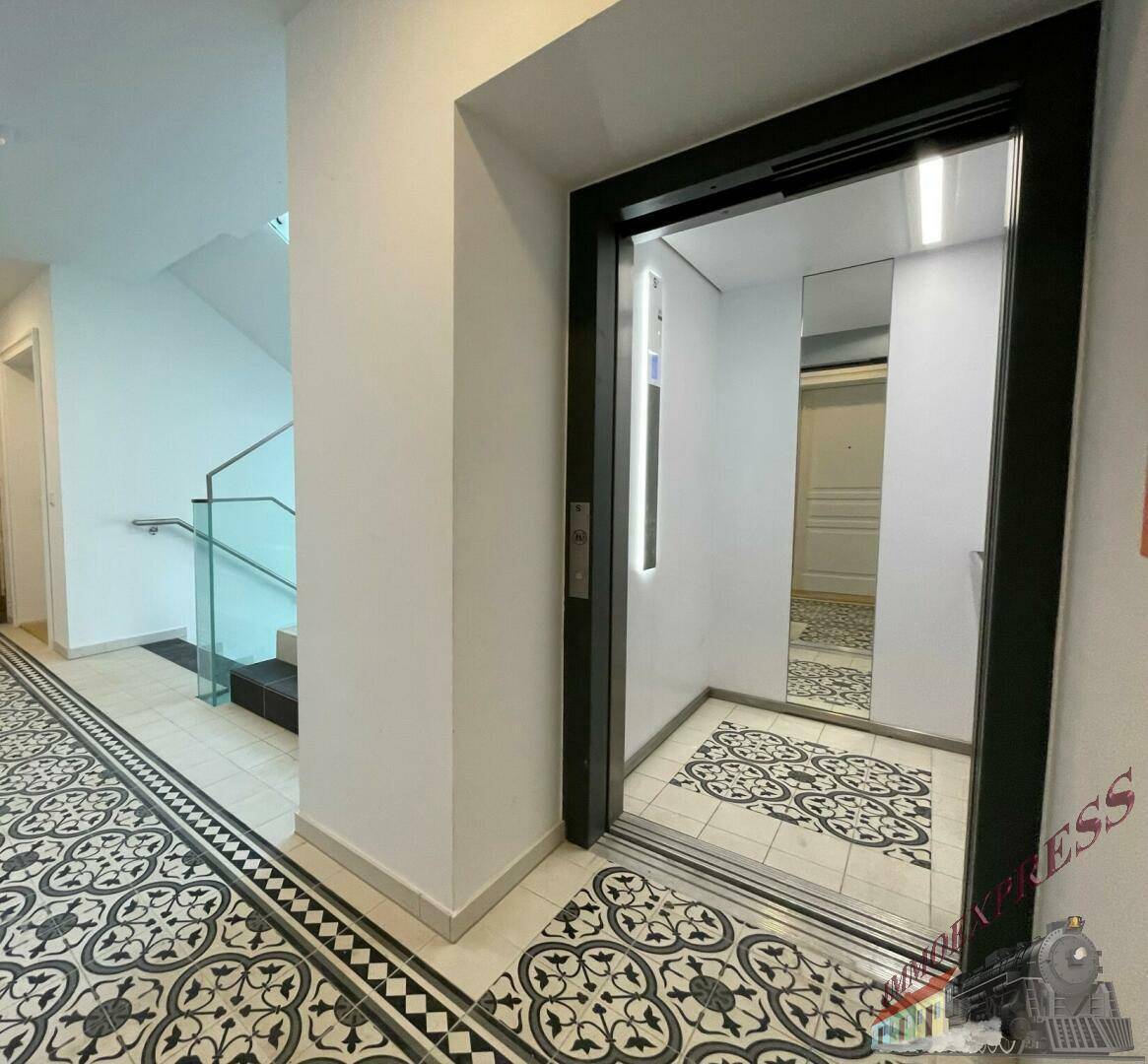 Eingangsbereich mit modernem Aufzug und stilvollem Fliesenboden im Altbau.