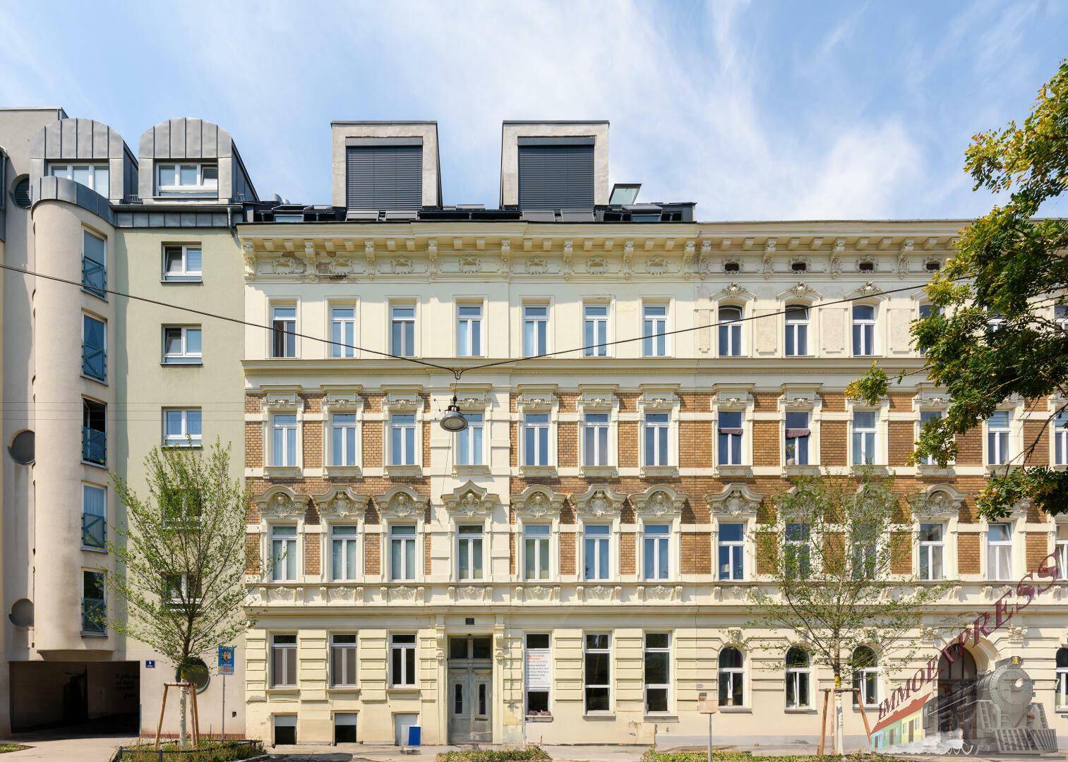 Historisches Mehrfamilienhaus mit klassischer Fassade und modernen Dachausbauten.