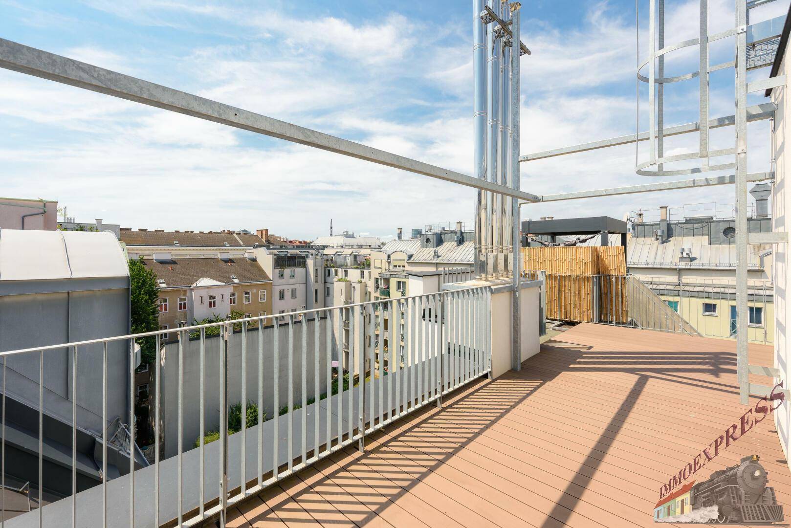 Geräumige Dachterrasse mit Holzdielenboden und Blick über die umliegenden Dächer der Stadt.