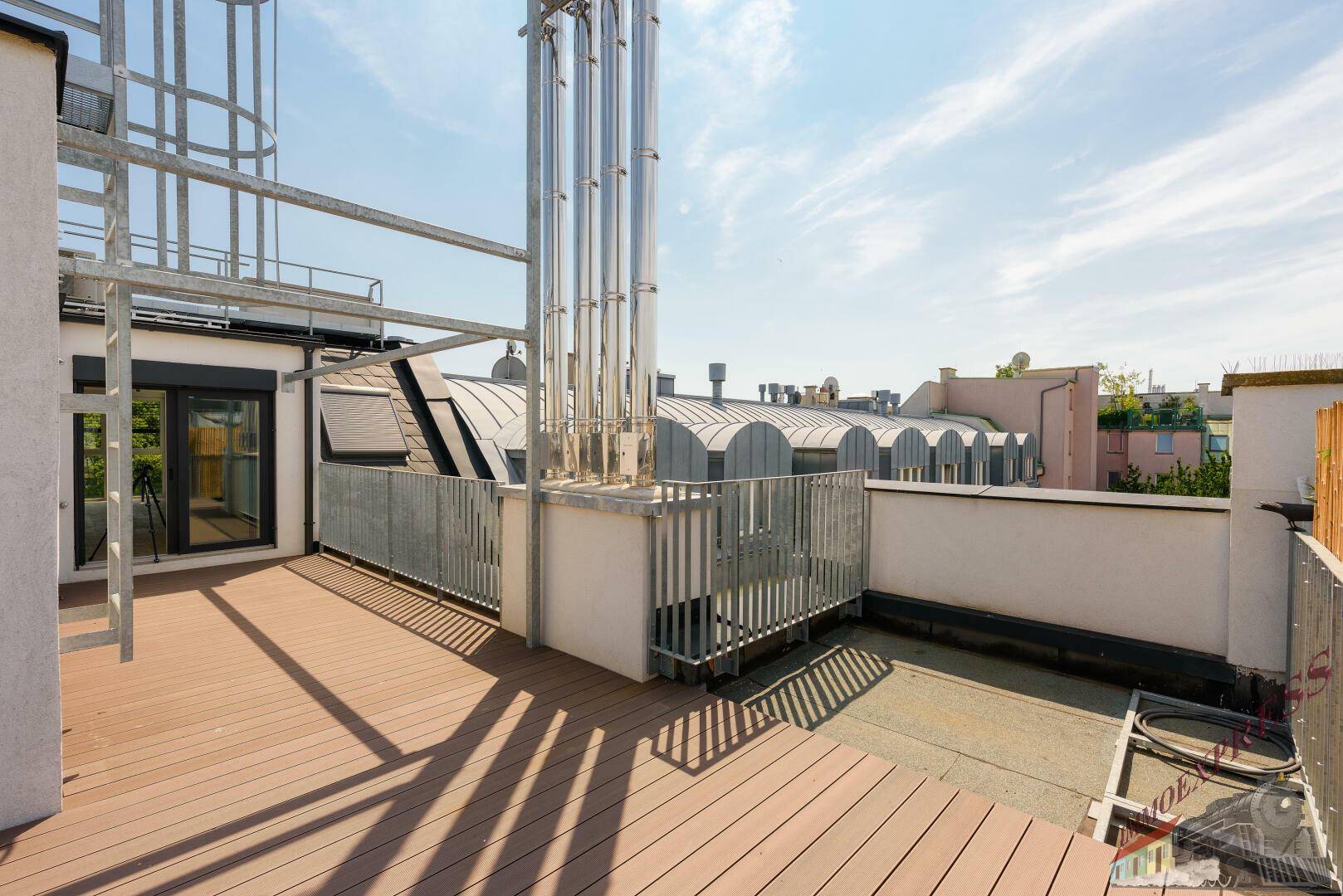 Großzügige Dachterrasse mit Holzdielen und Blick auf die städtische Umgebung.