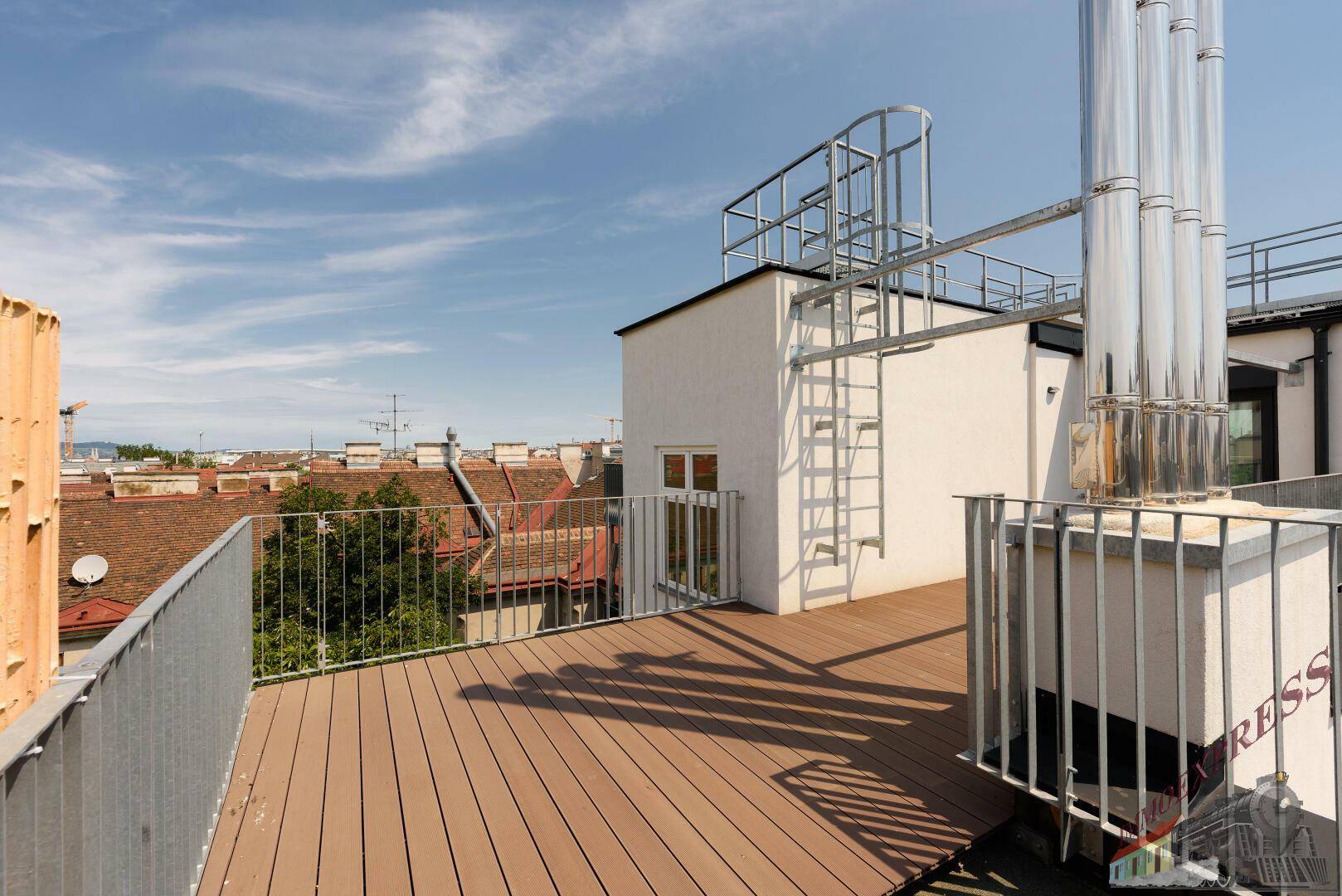 Weitläufige Dachterrasse mit Holzdielen und Blick auf die umliegenden Gebäude.