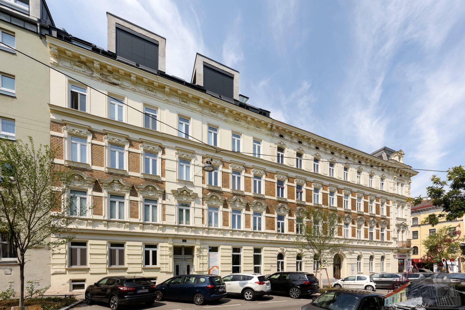 Historisches Gebäude mit reich verzierter Fassade und modernen Dachaufbauten.