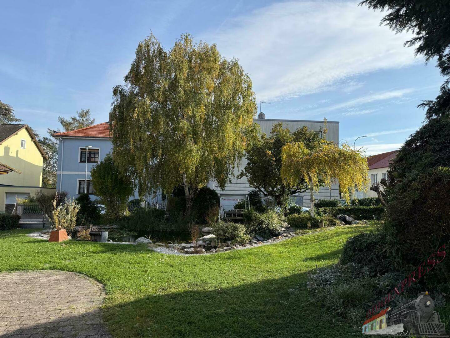 Großer, gepflegter Garten mit Rasenfläche und verschiedenen Bäumen im Hintergrund.