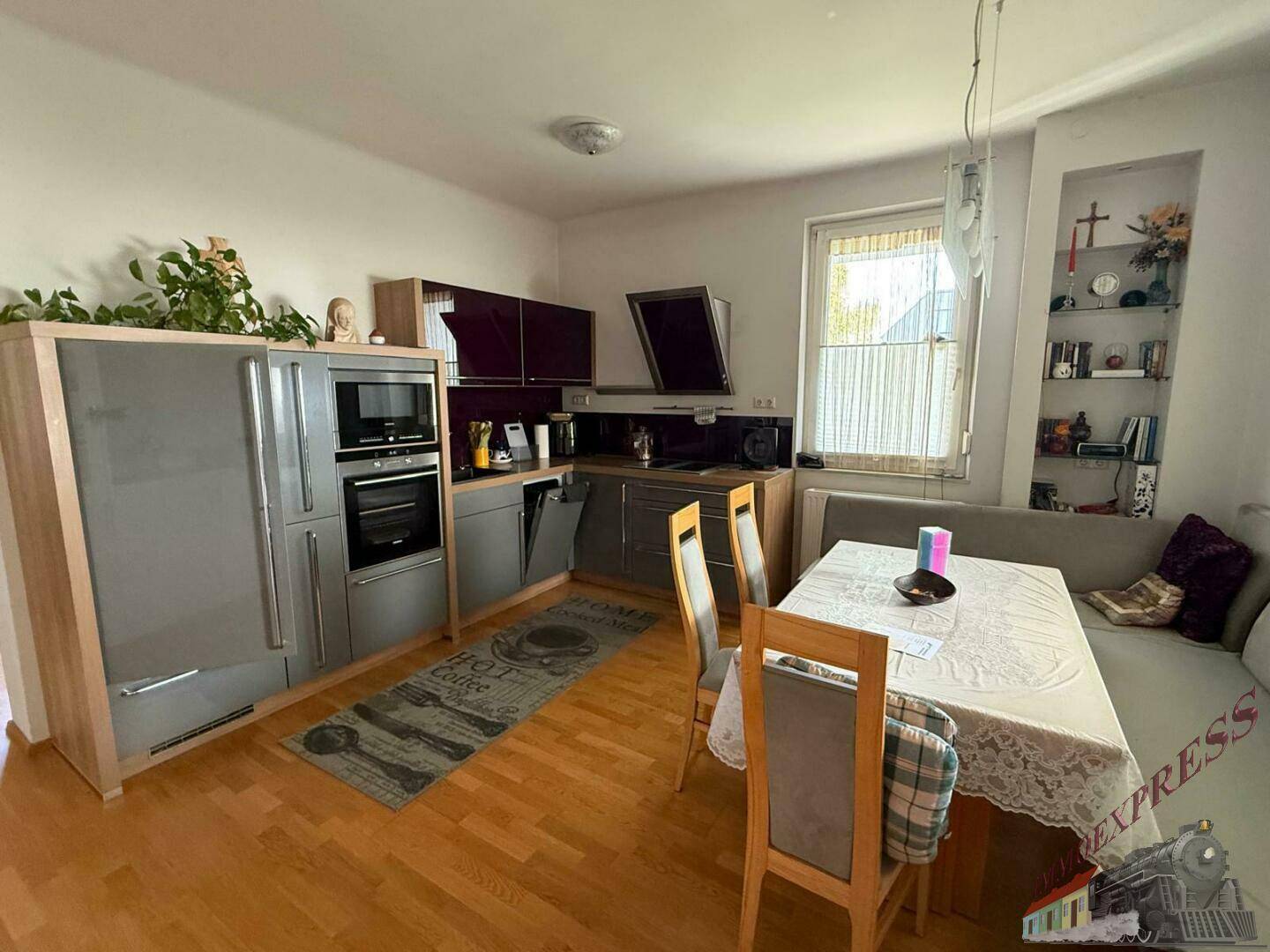 Moderne Einbauküche mit Essbereich, grauen Schränken und integrierten Geräten.