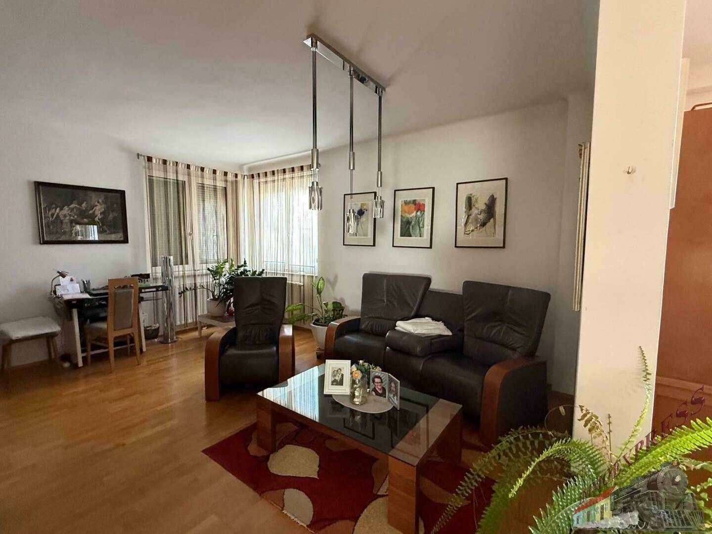 Helles Wohnzimmer mit Holzboden, Ledermöbeln und dekorativen Bildern an der Wand.