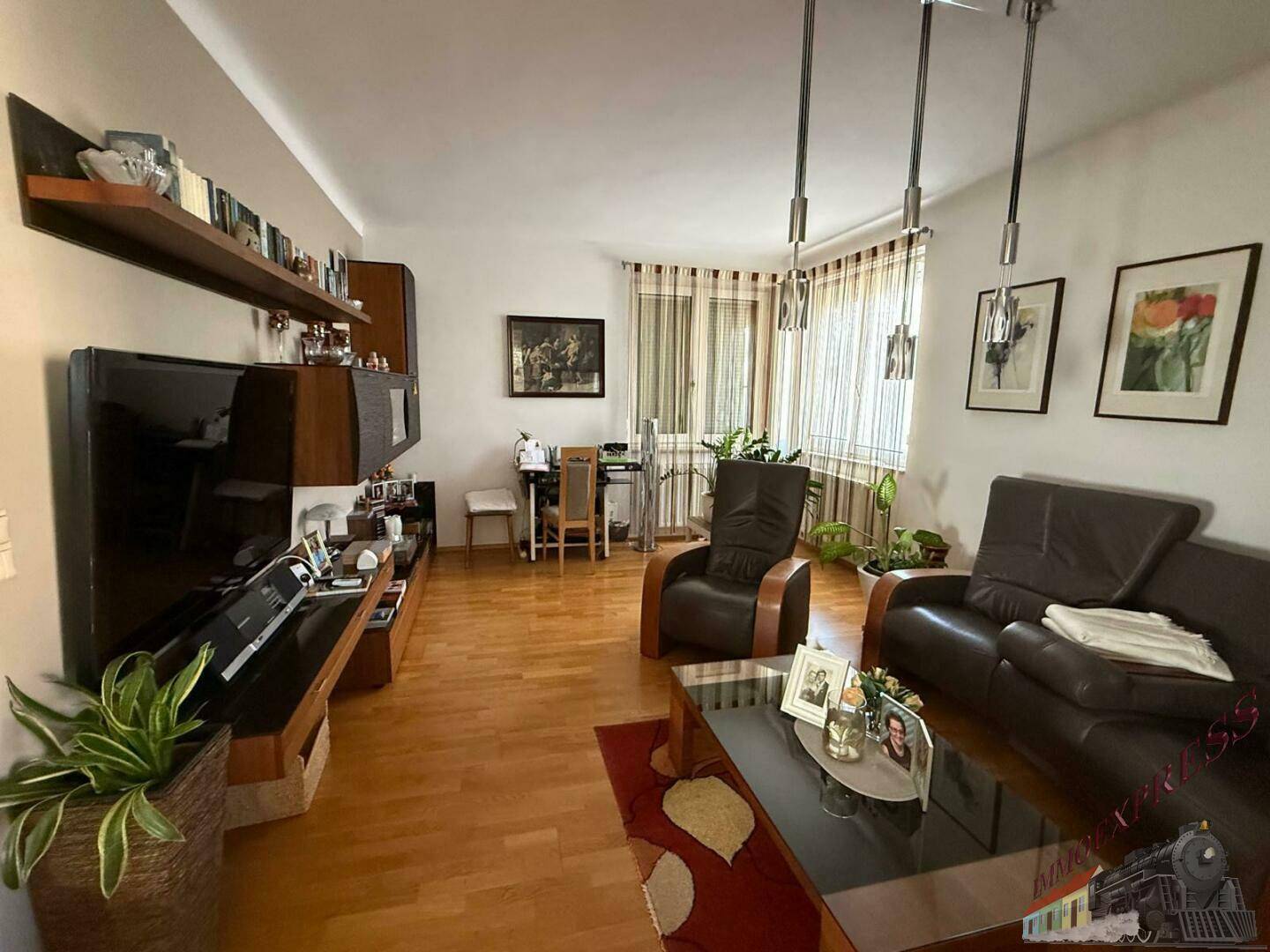 Gemütliches Wohnzimmer mit Holzboden, bequemen Ledersofas und großem Fernseher.