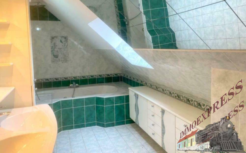 Badezimmer mit grünen Fliesen, Badewanne und Waschtisch unter Dachschräge.