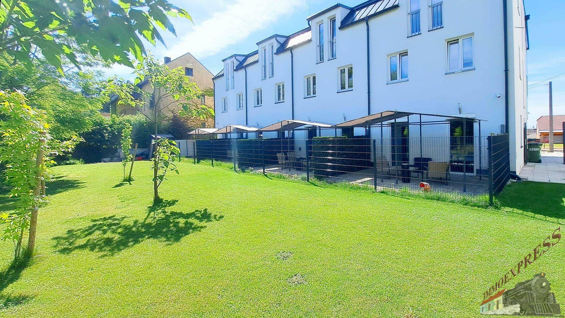 Weitläufiger Garten mit grüner Rasenfläche und angrenzenden Terrassenbereichen des Gebäudes.