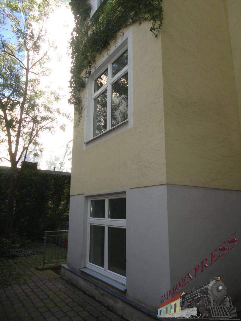 Seitenansicht des Gebäudes mit hellen Fenstern und üppigem Efeu, der an der Fassade wächst.