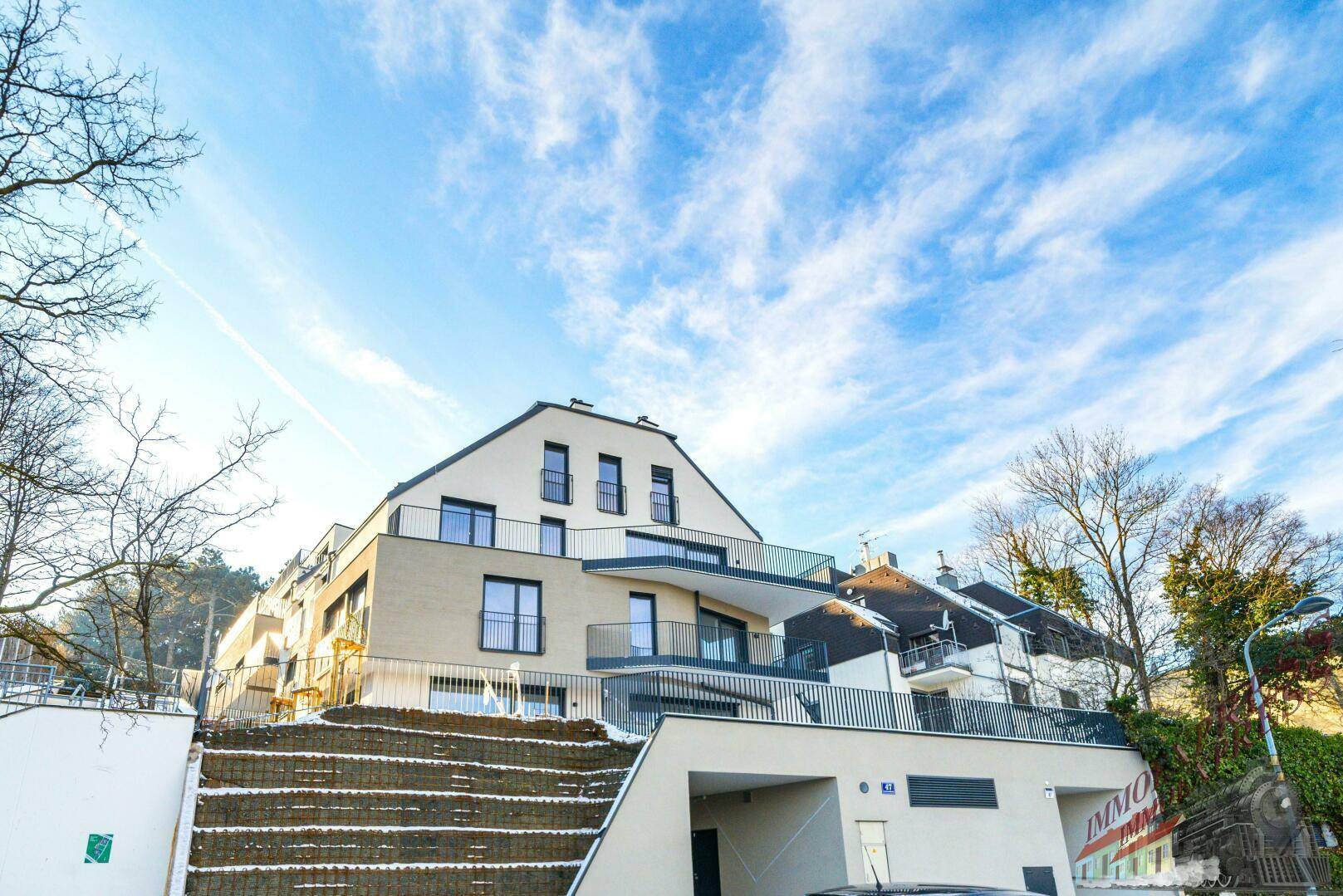 Modernes Mehrfamilienhaus mit Balkonen, Tiefgaragenzufahrt und gepflegter Außenanlage im Winter.
