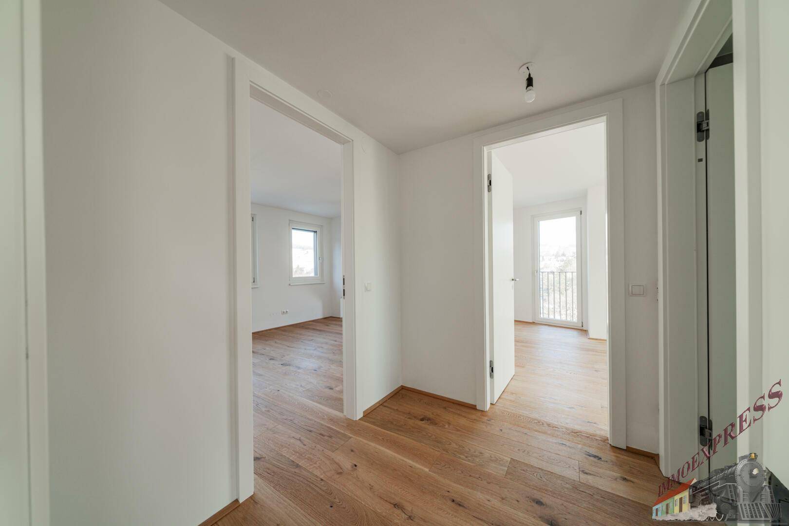 Heller Flur mit Holzboden und offenen Türen zu weiteren Zimmern.