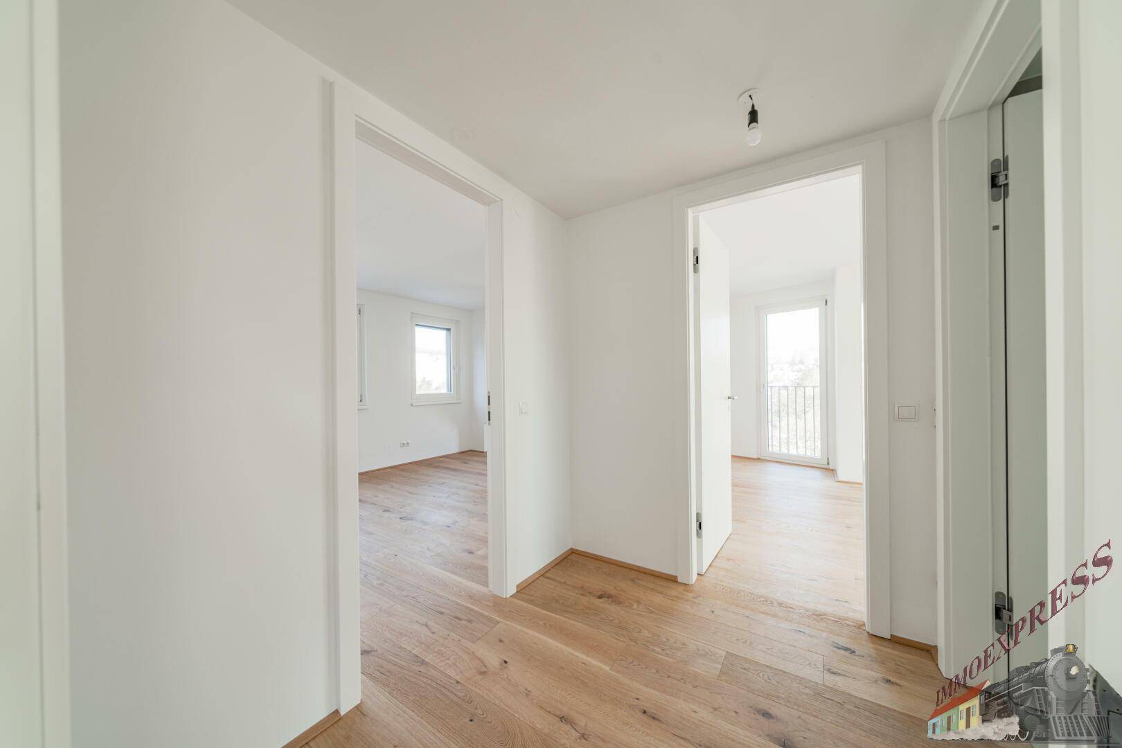 Heller Flur mit Holzboden und offenen Türen zu weiteren Zimmern.