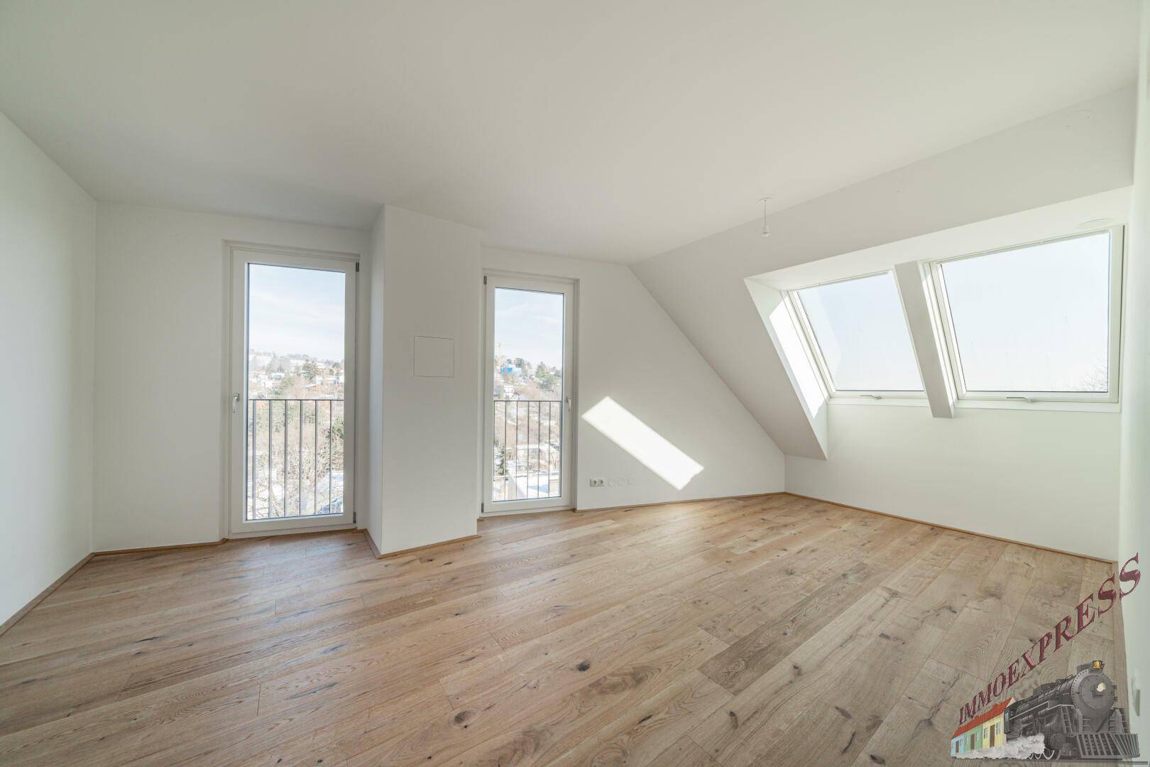 Geräumiges Zimmer mit Holzboden, zwei französischen Balkonen und Dachfenstern.