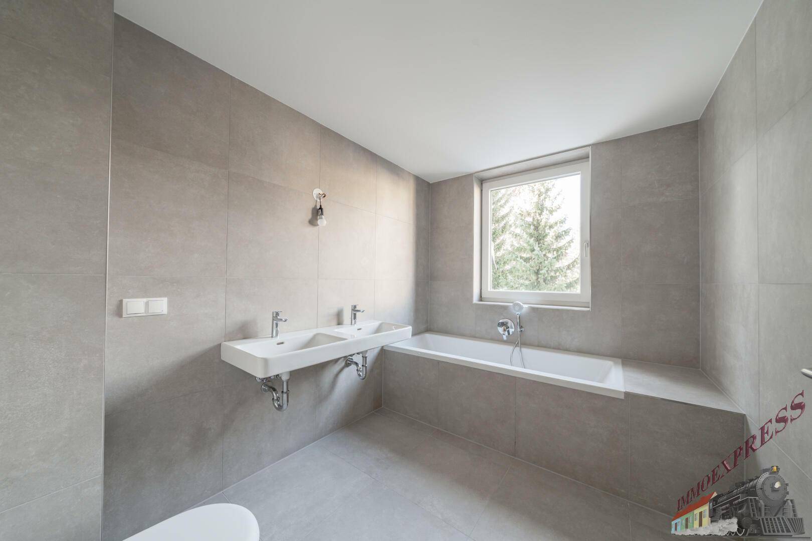 Modernes Badezimmer mit Badewanne, Doppelwaschbecken und Fenster für Tageslicht.