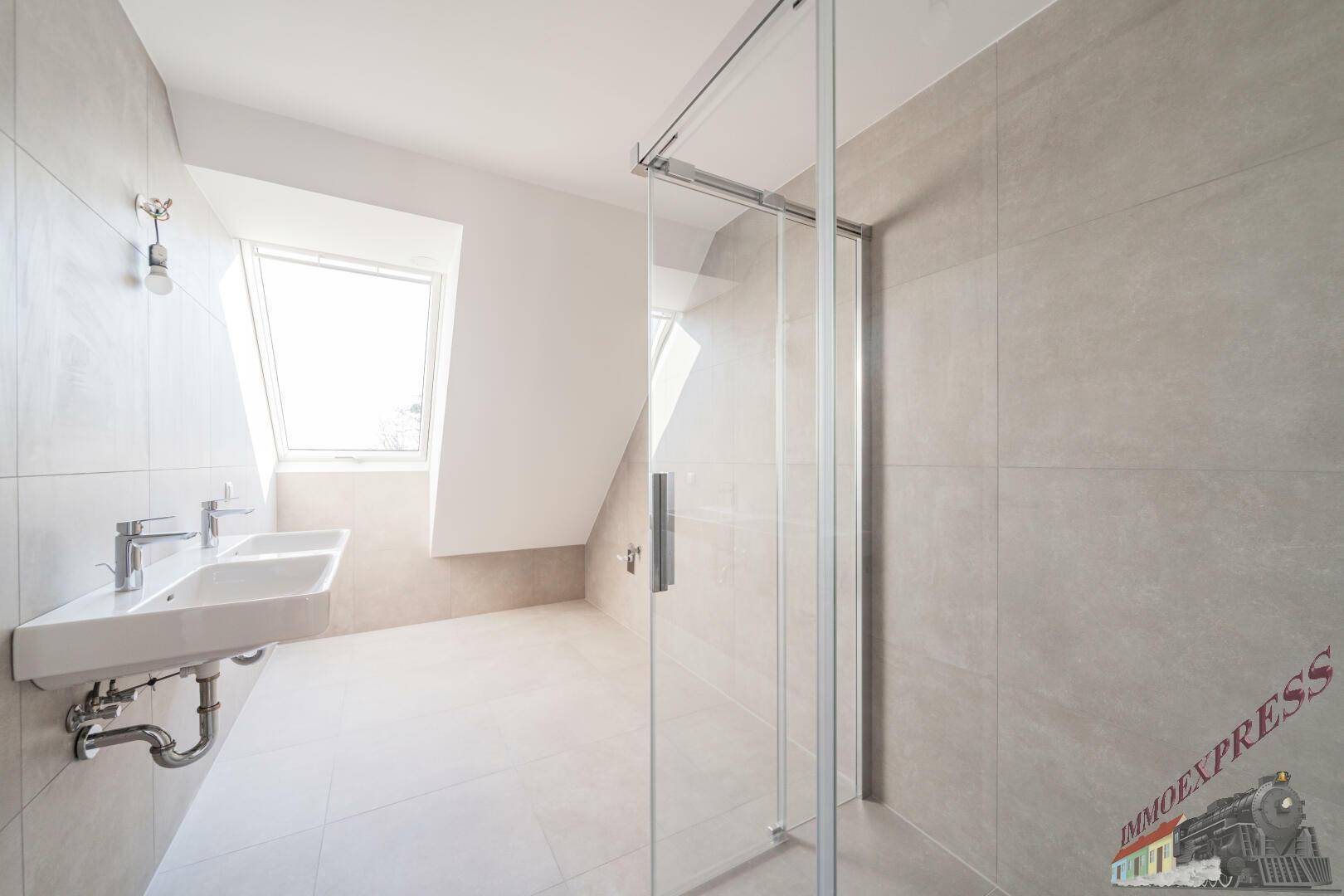 Modernes Badezimmer mit Doppelwaschbecken, großer Dusche und Dachfenster für natürliches Licht.