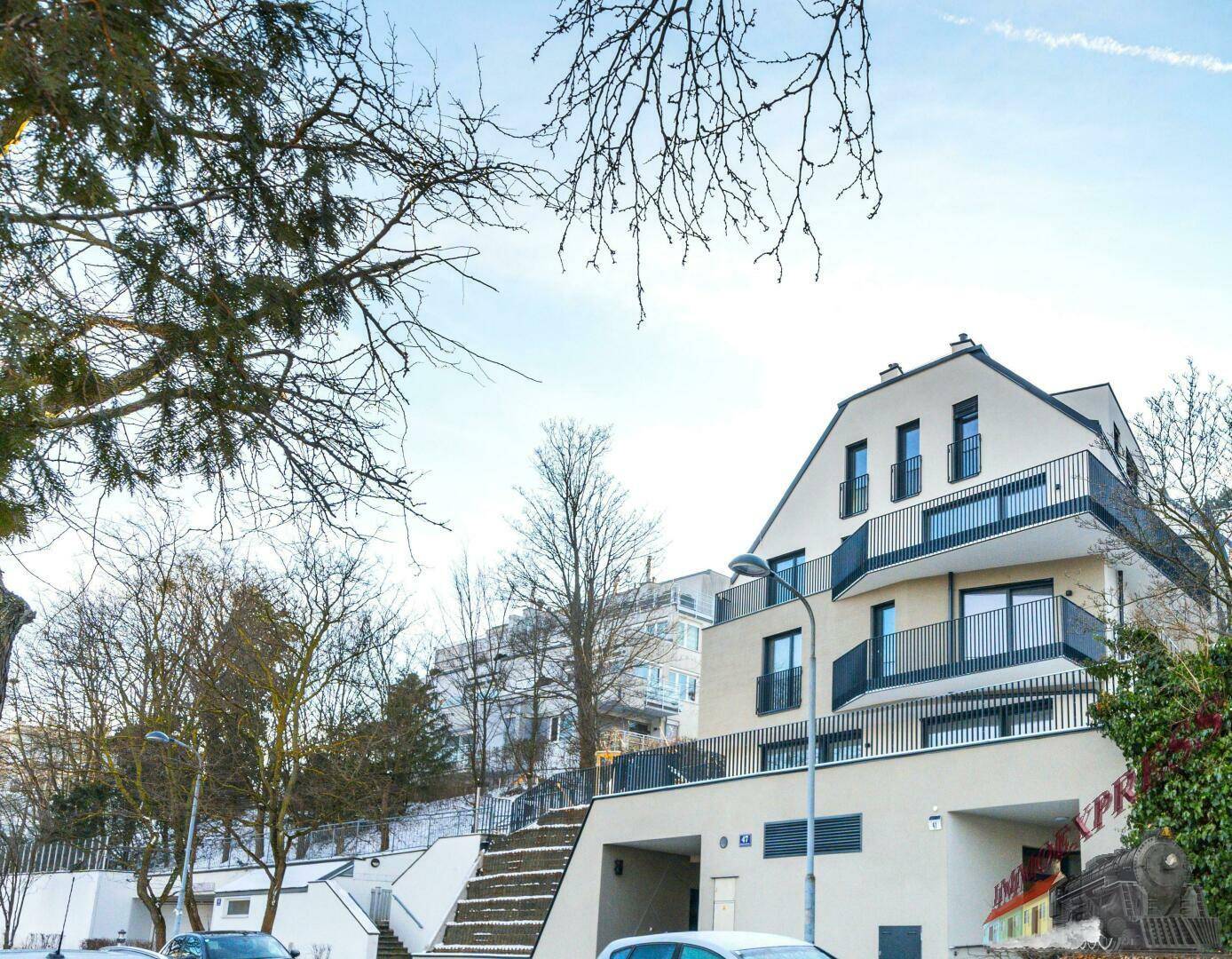 Winteransicht der modernen Wohnanlage mit Balkonen und umliegender Natur.
