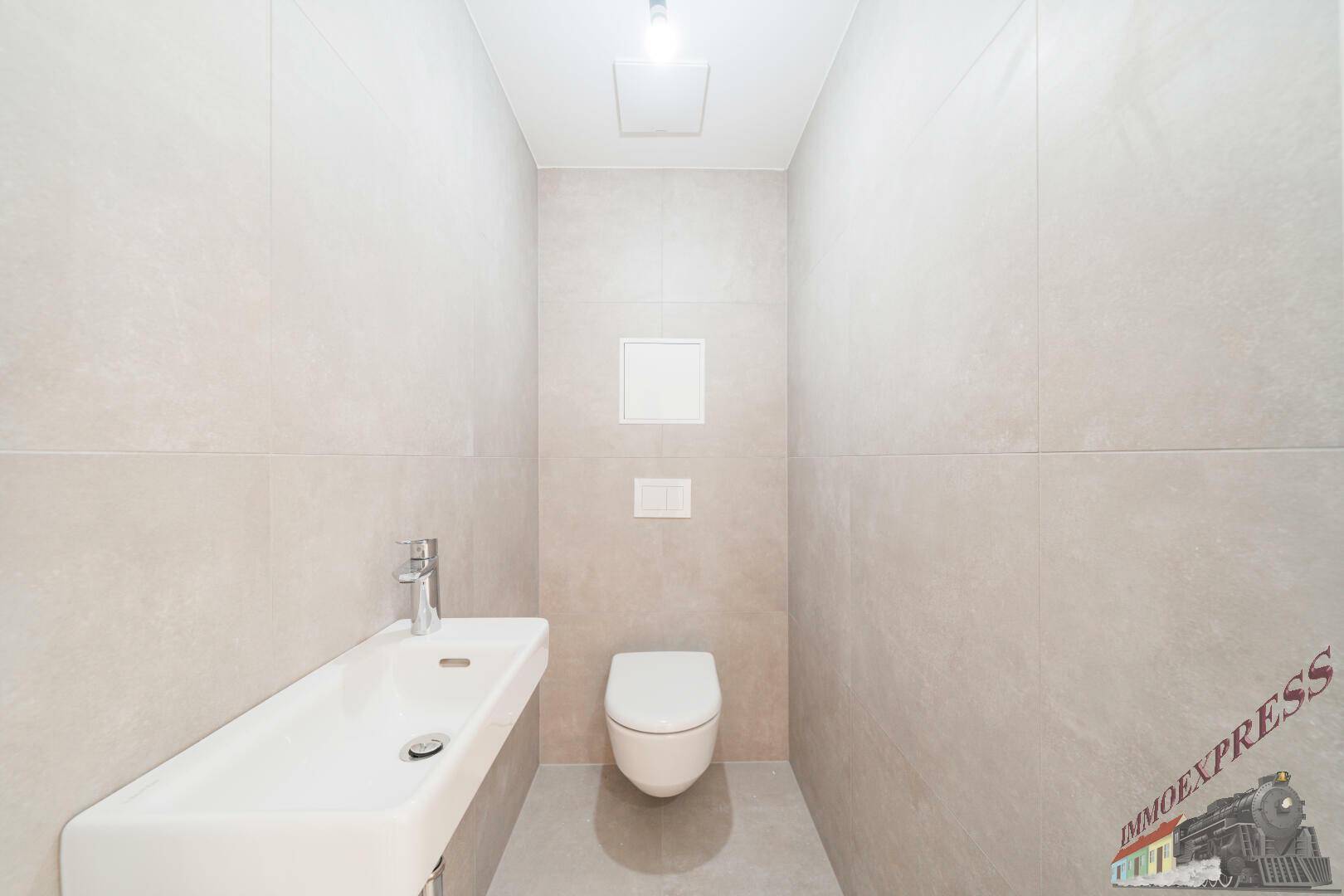 Modernes Gäste-WC mit wandhängender Toilette und kleinem Waschbecken, hell gefliest.