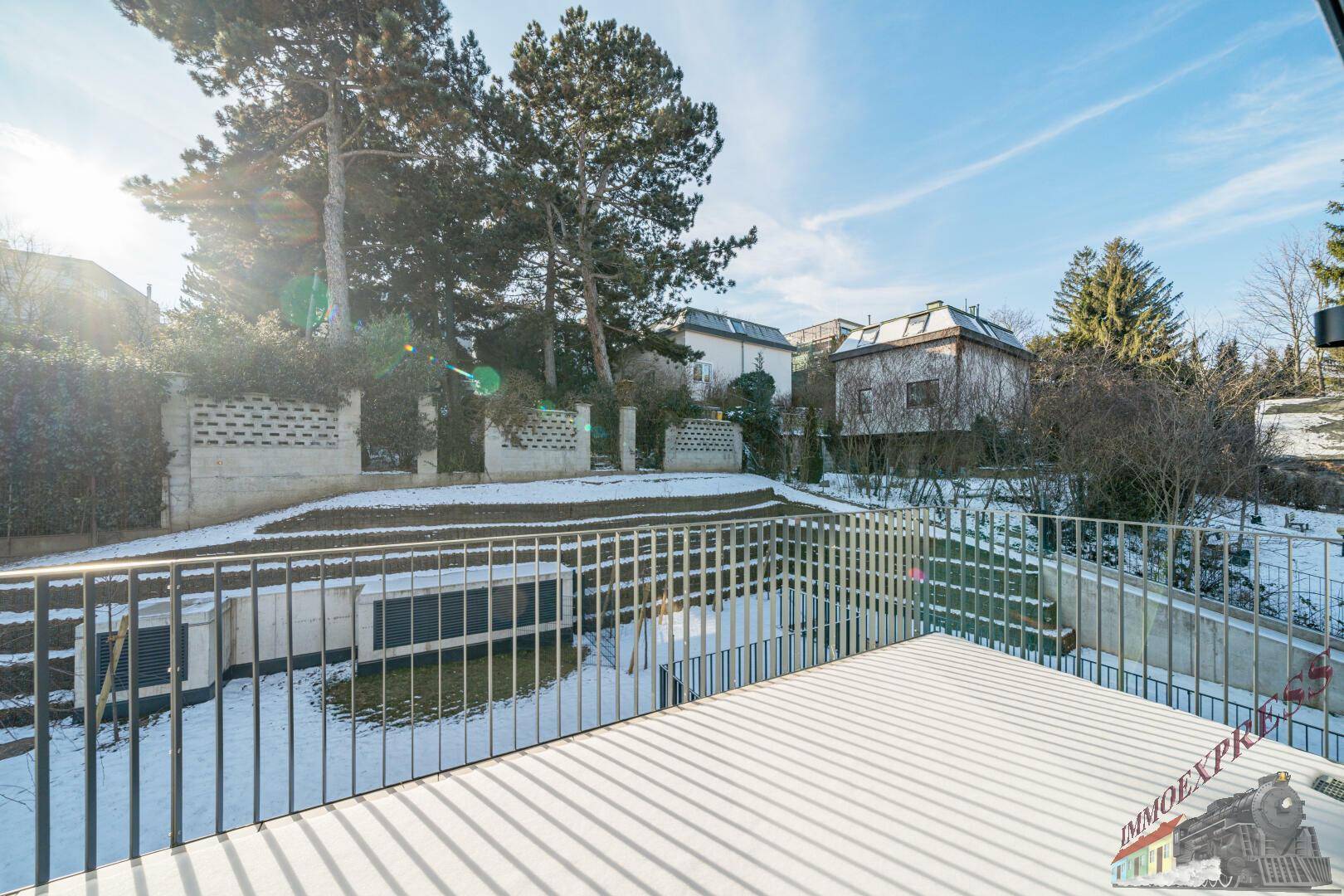 Terrasse im Winter mit leichter Schneedecke und Blick auf die verschneite Gartenlandschaft.