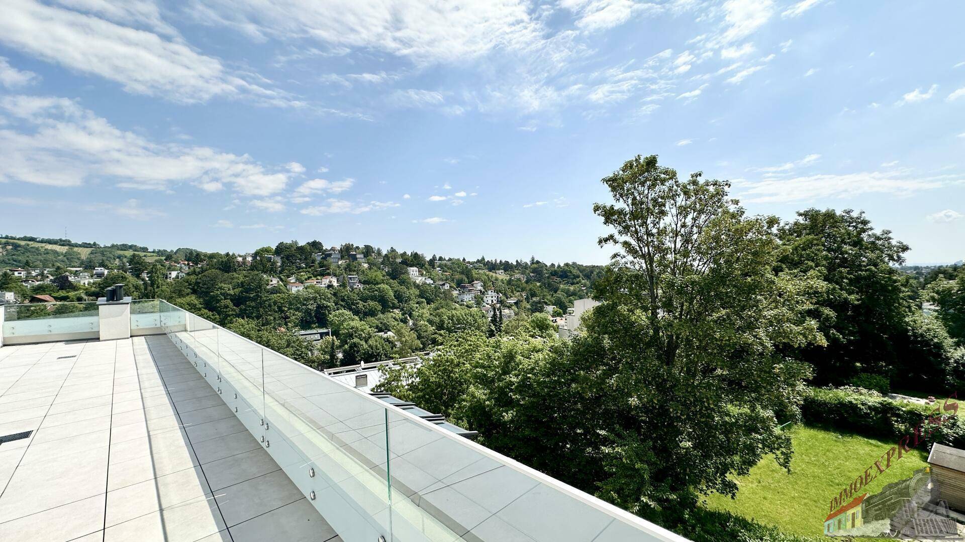 Panoramablick von der Terrasse über die grüne Hügellandschaft und die umliegenden Häuser.