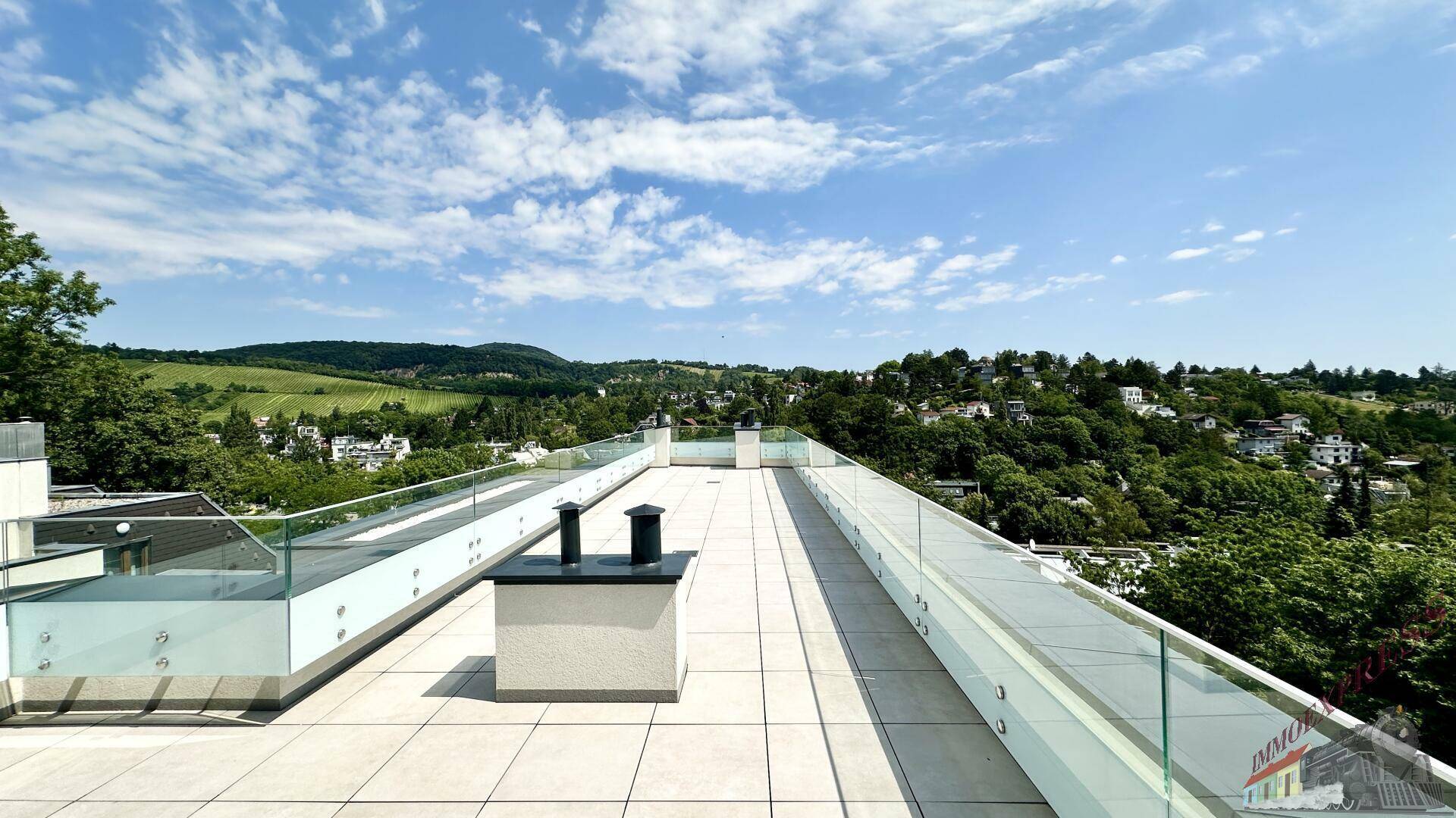 Weitläufige Dachterrasse mit Fliesenboden und Glasgeländer, ideal für Entspannung im Freien.