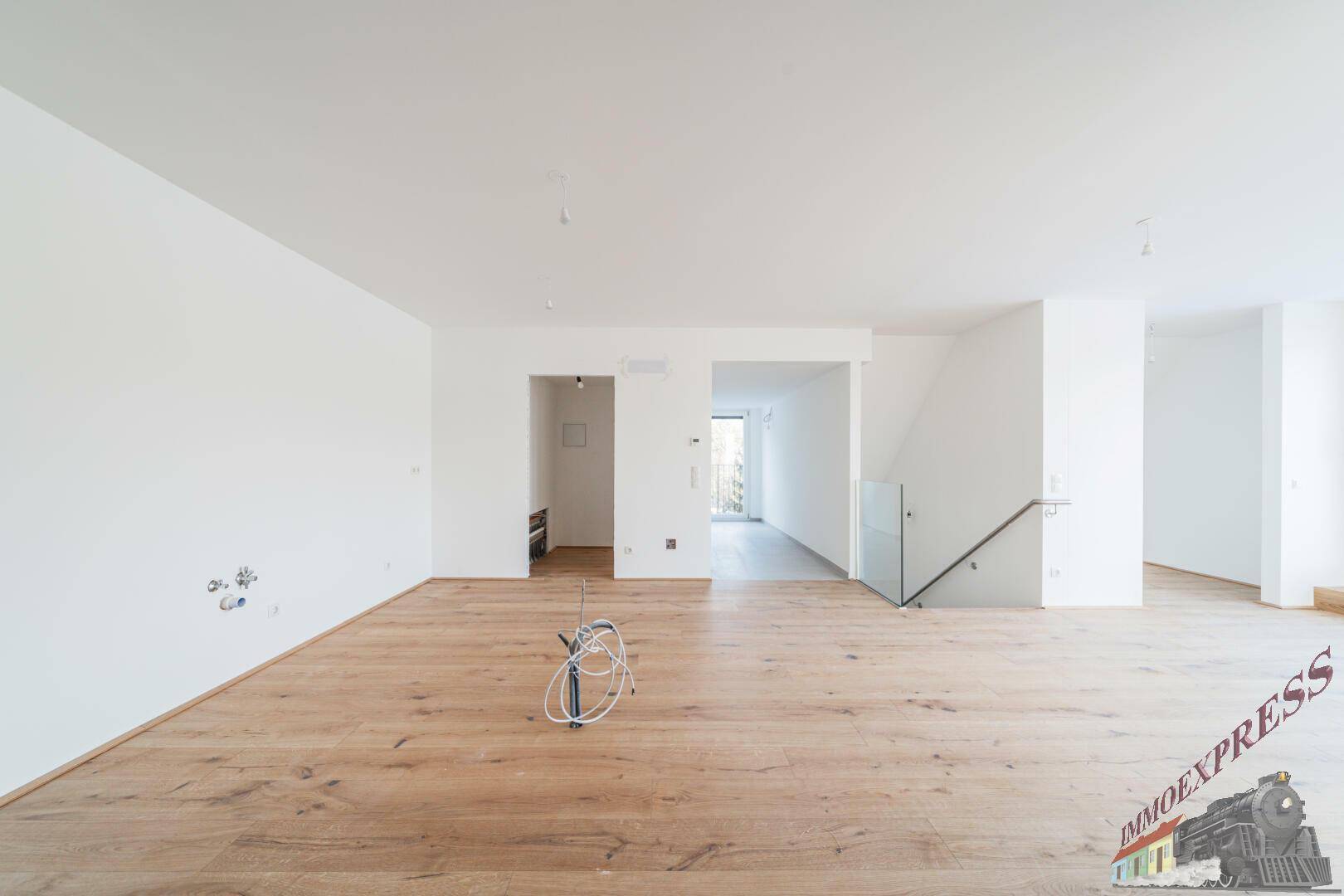 Geräumiger, heller Wohnbereich mit Holzboden und minimalistischem Design, ideal für modernes Wohnen.