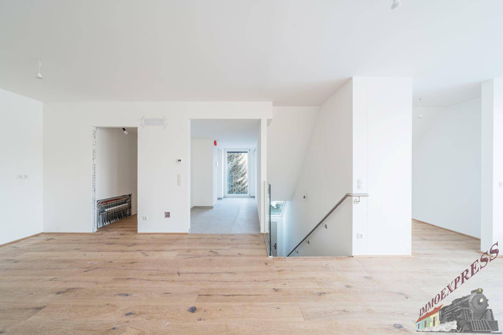 Offener Wohnbereich mit Holzboden und moderner Treppe, die die Etagen verbindet.