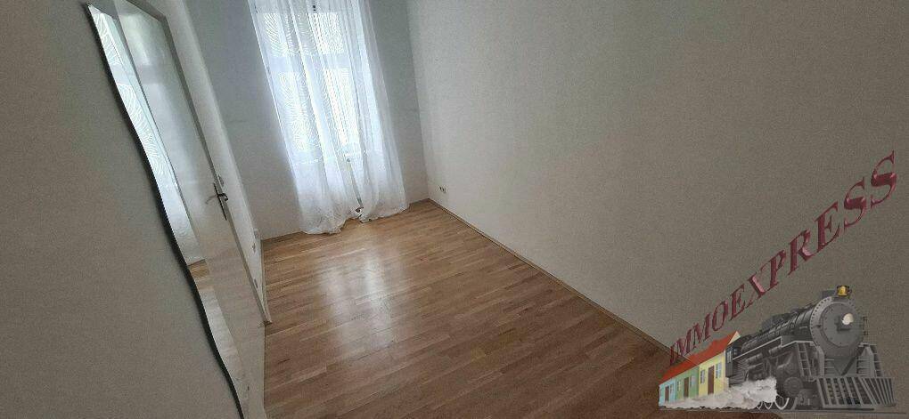 Freundliches Zimmer mit hellem Parkettboden und viel Tageslicht durch die Fenster.