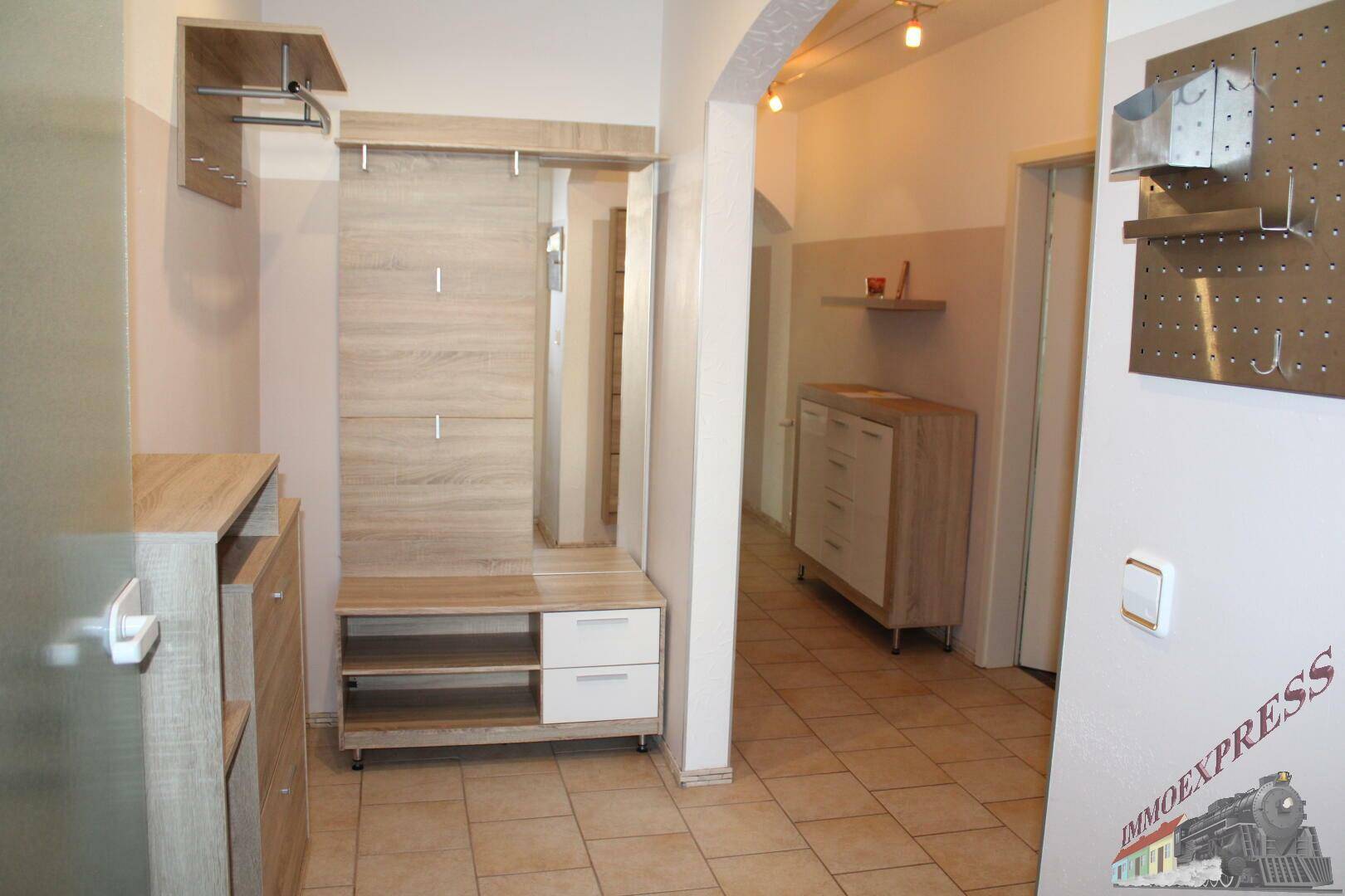 Eingangsbereich mit Garderobe, Spiegel und Fliesenboden.