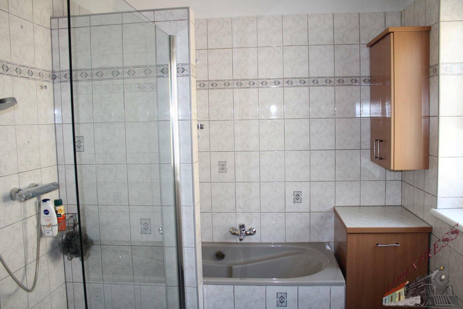 Badezimmer mit Badewanne, Duschkabine und hellen Fliesen.