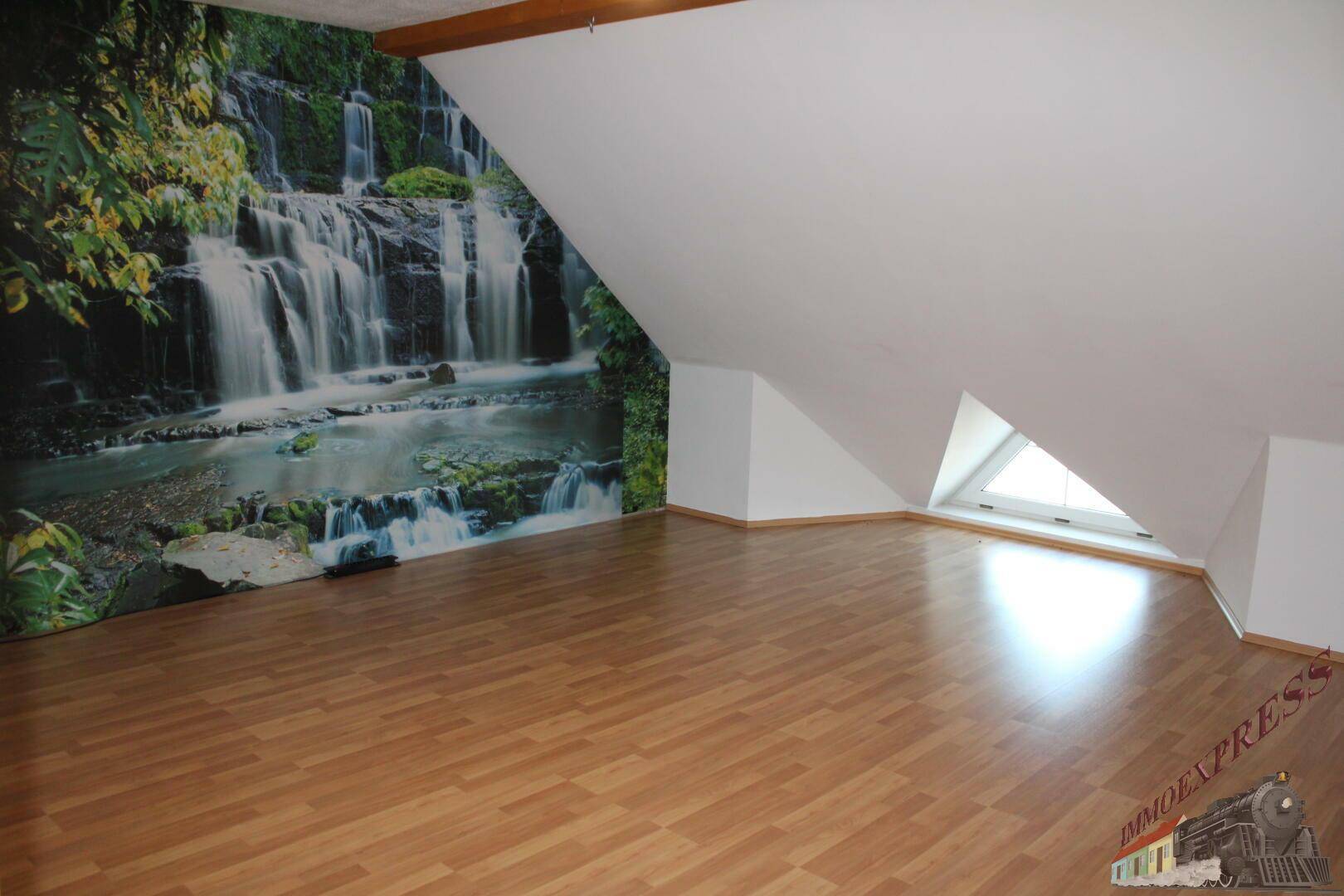 Geräumiges Schlafzimmer im Dachgeschoss mit Laminatboden und Wasserfall-Tapete.