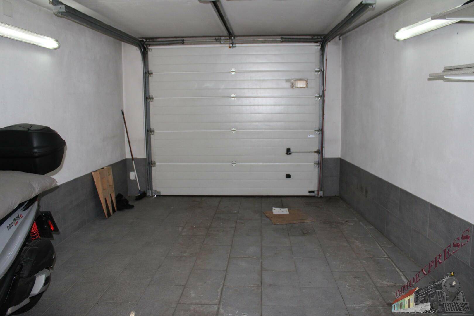 Geräumige Garage mit Sektionaltor und Fliesenboden.