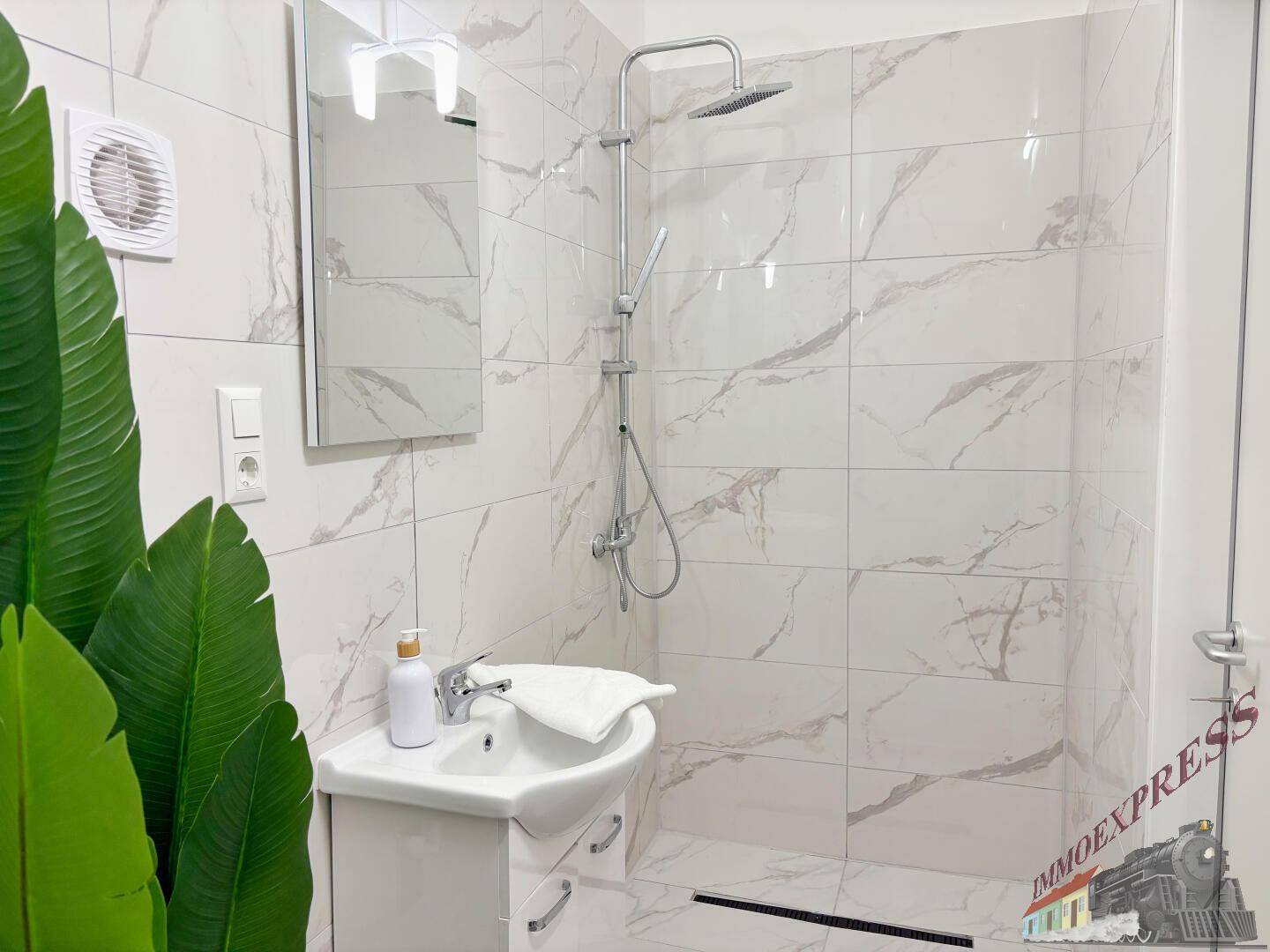 Modernes Badezimmer mit Waschbecken, Spiegel, Duschbereich und Abluftventilator.