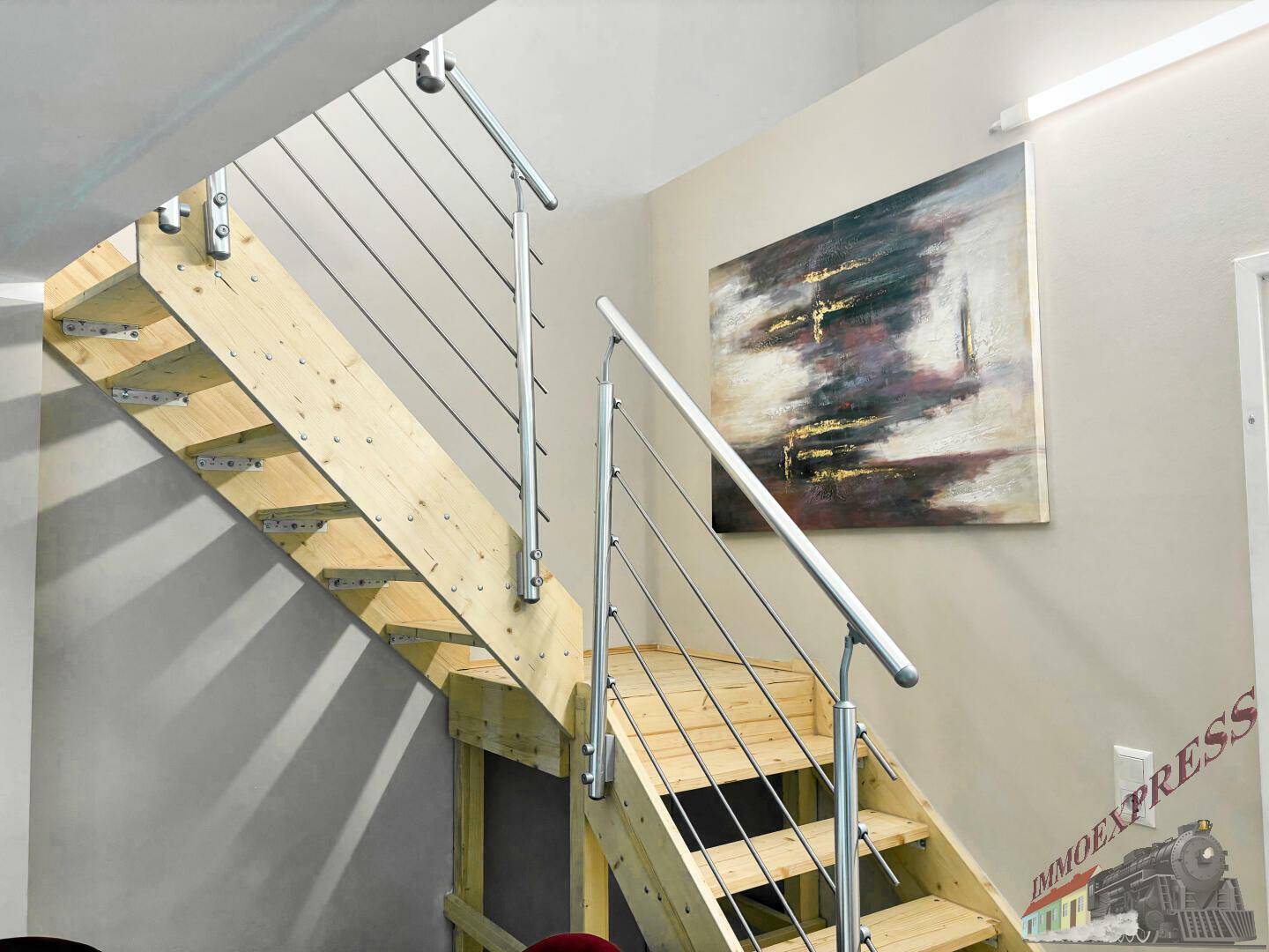 Moderne Holztreppe mit Edelstahlgeländer und einem abstrakten Kunstwerk an der Wand.