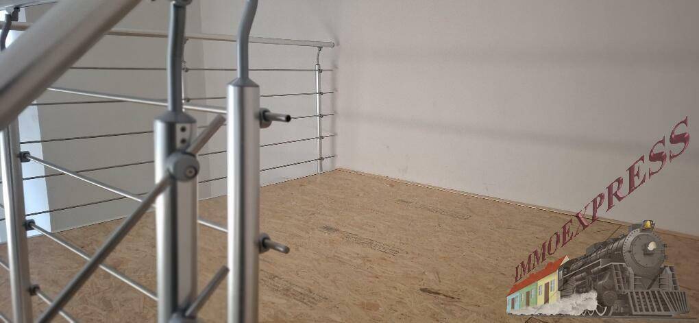 Oberer Treppenabsatz mit unfertigem Holzfußboden und modernem Edelstahlgeländer.