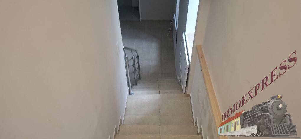 Blick von oben auf eine geflieste Treppe, die in ein tiefer gelegenes Stockwerk führt.