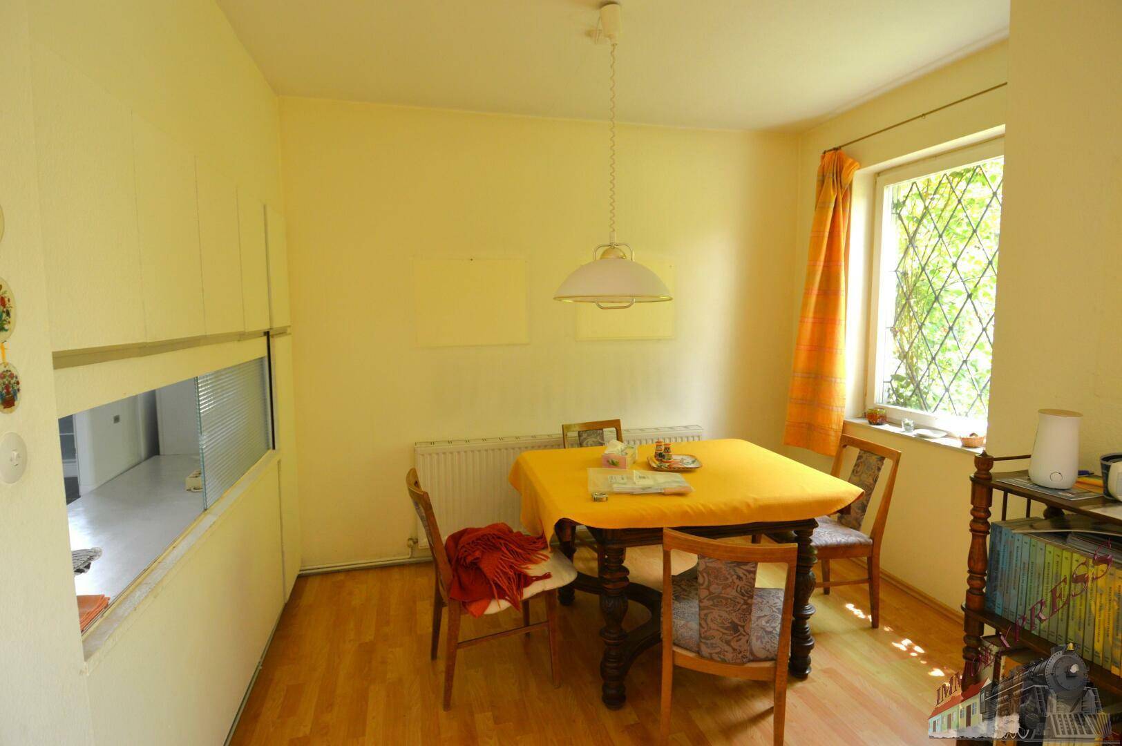 Gemütlicher Essbereich mit Laminatboden, einem Esstisch und Blick ins Grüne durch das Fenster.