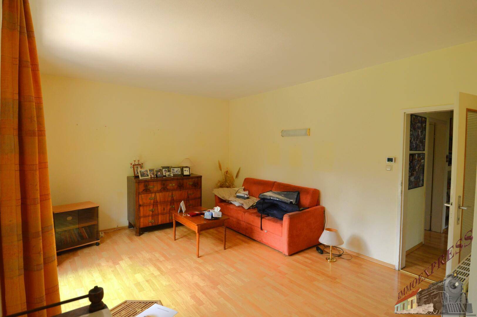 Wohnzimmer mit Laminatboden, einem Sofa und einem Fenster mit Blick in den Garten.