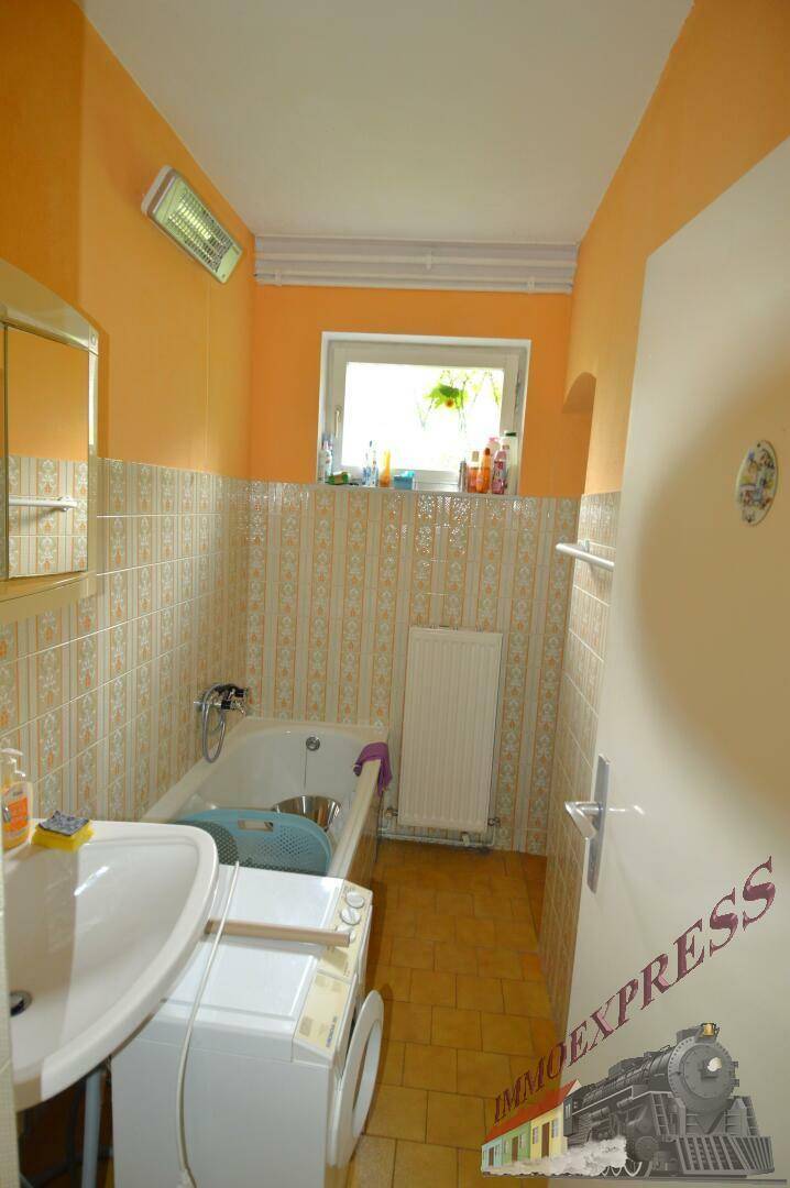 Badezimmer mit Badewanne, Waschbecken, Waschmaschine und einem Fenster für natürliche Belüftung.