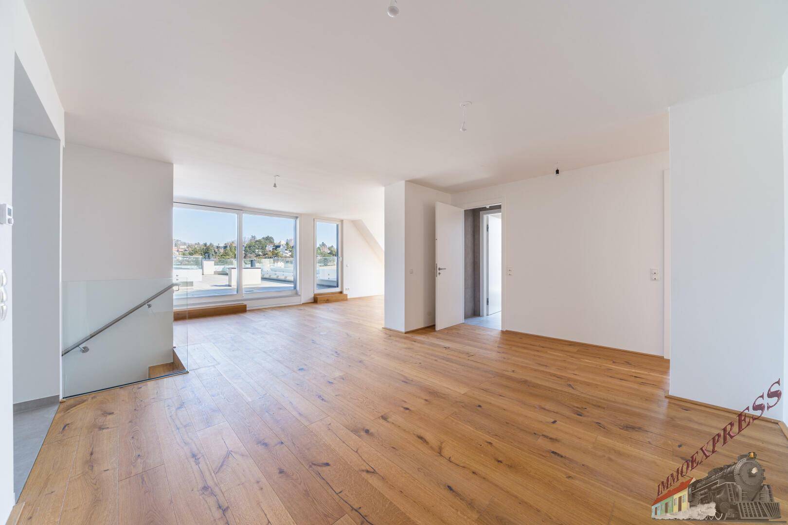 Geräumiger, heller Wohnbereich mit Holzboden und moderner Treppe, bereit für die Einrichtung.