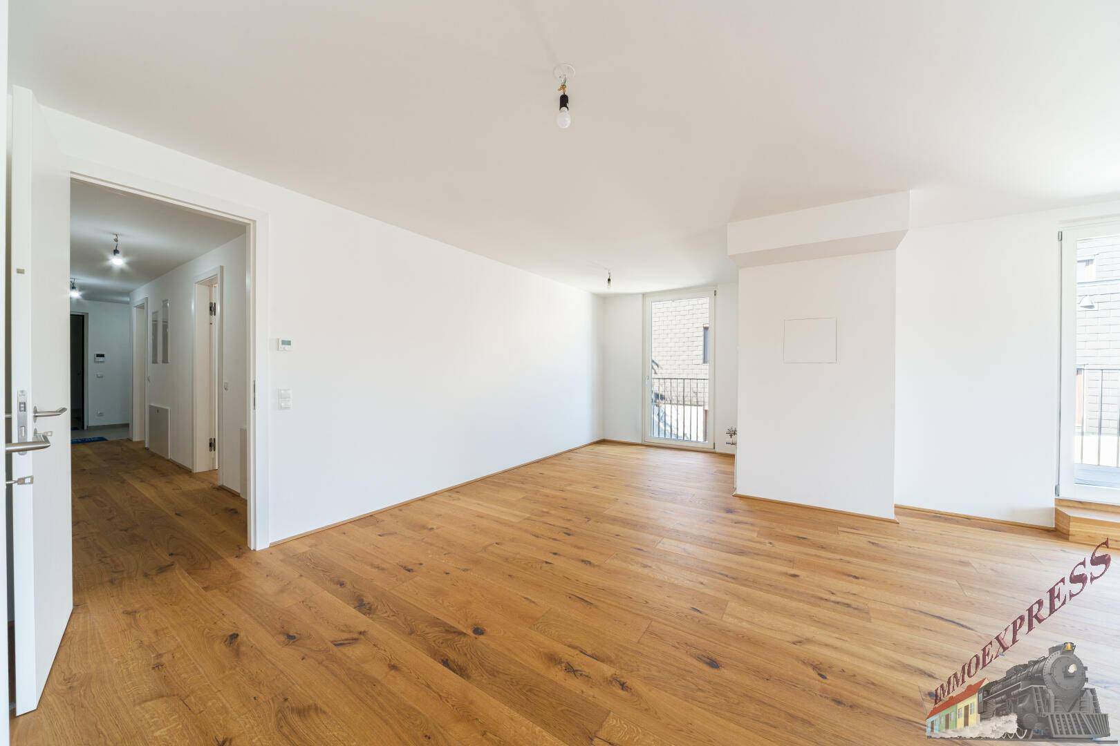 Heller Wohnraum mit Holzboden und Zugang zu einem Flur, bereit zur Gestaltung.