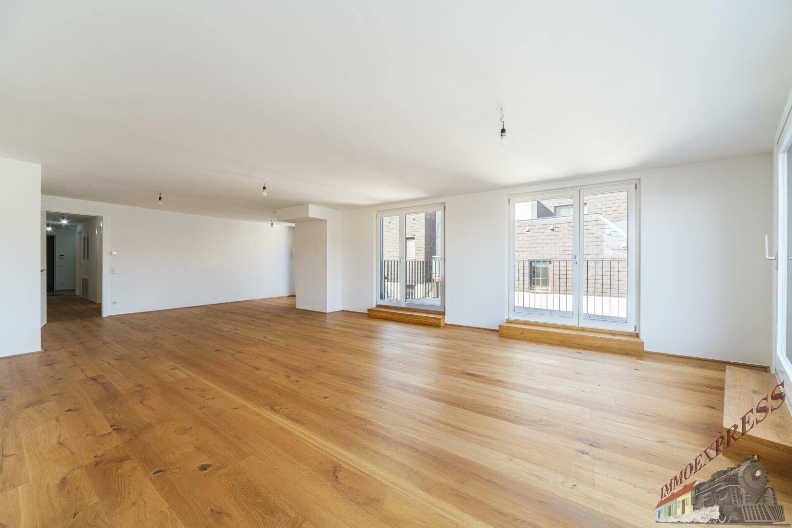 Geräumiger Wohnbereich mit Holzboden und hellen Wänden, bereit zum Einrichten.