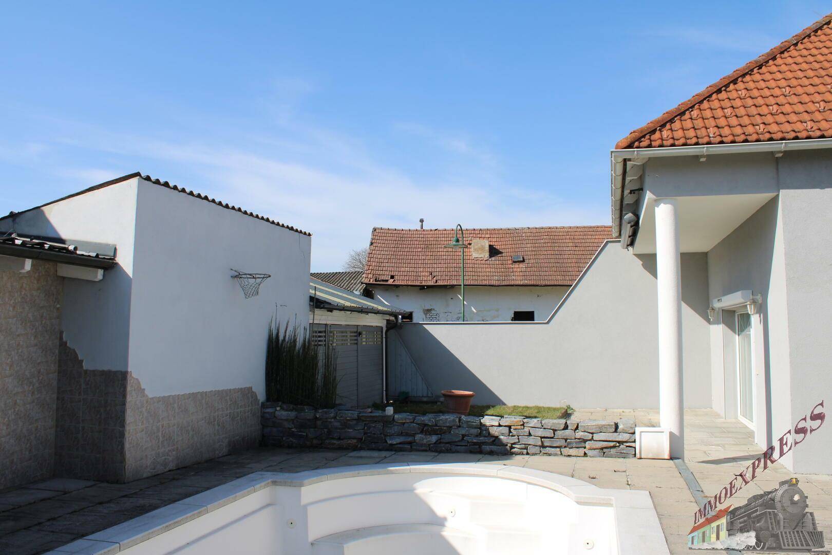 Rückansicht des Hauses mit Poolbereich und angrenzenden Gebäuden.