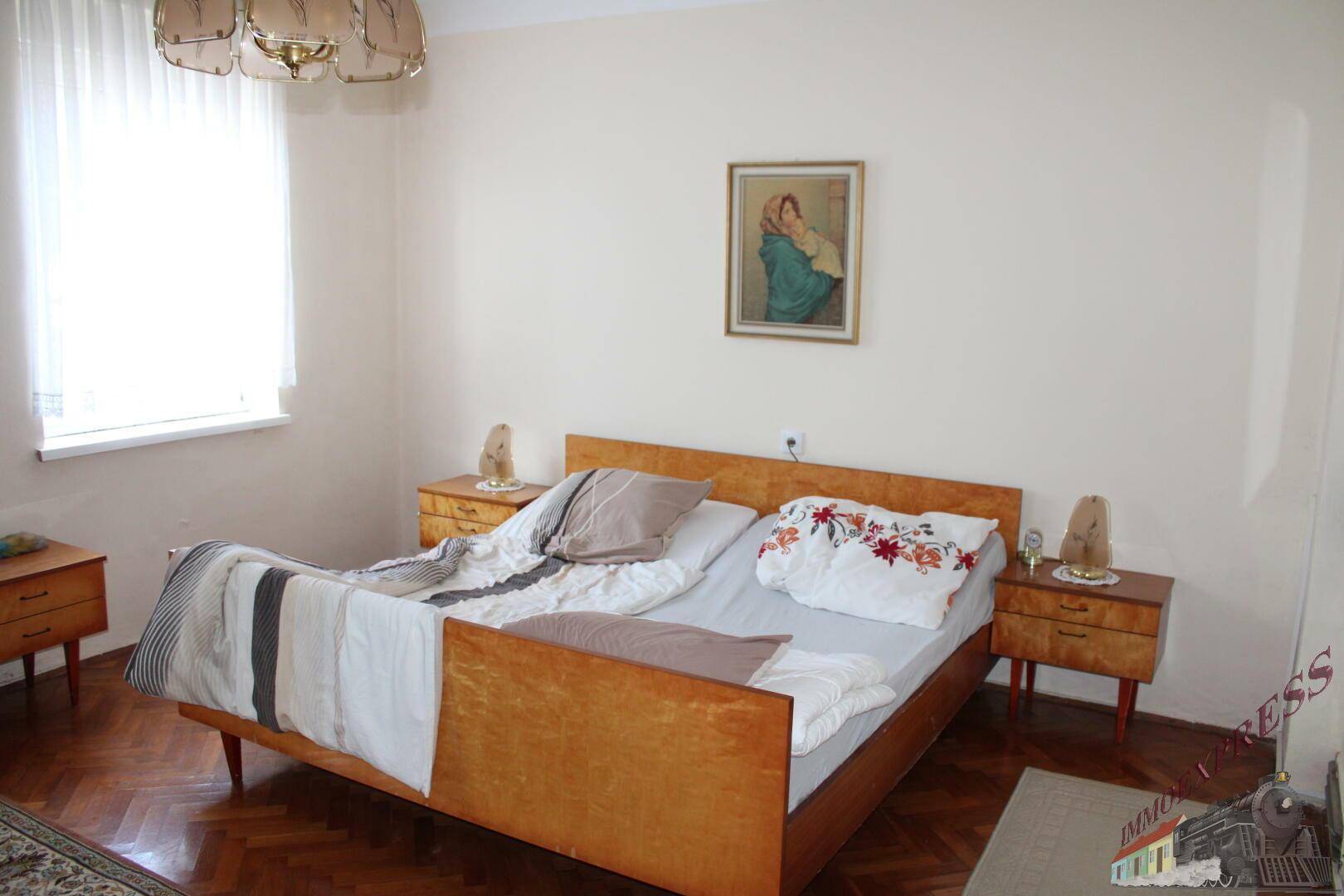 Schlafzimmer mit Doppelbett, Nachttischen und Parkettboden, bietet eine ruhige Atmosphäre.