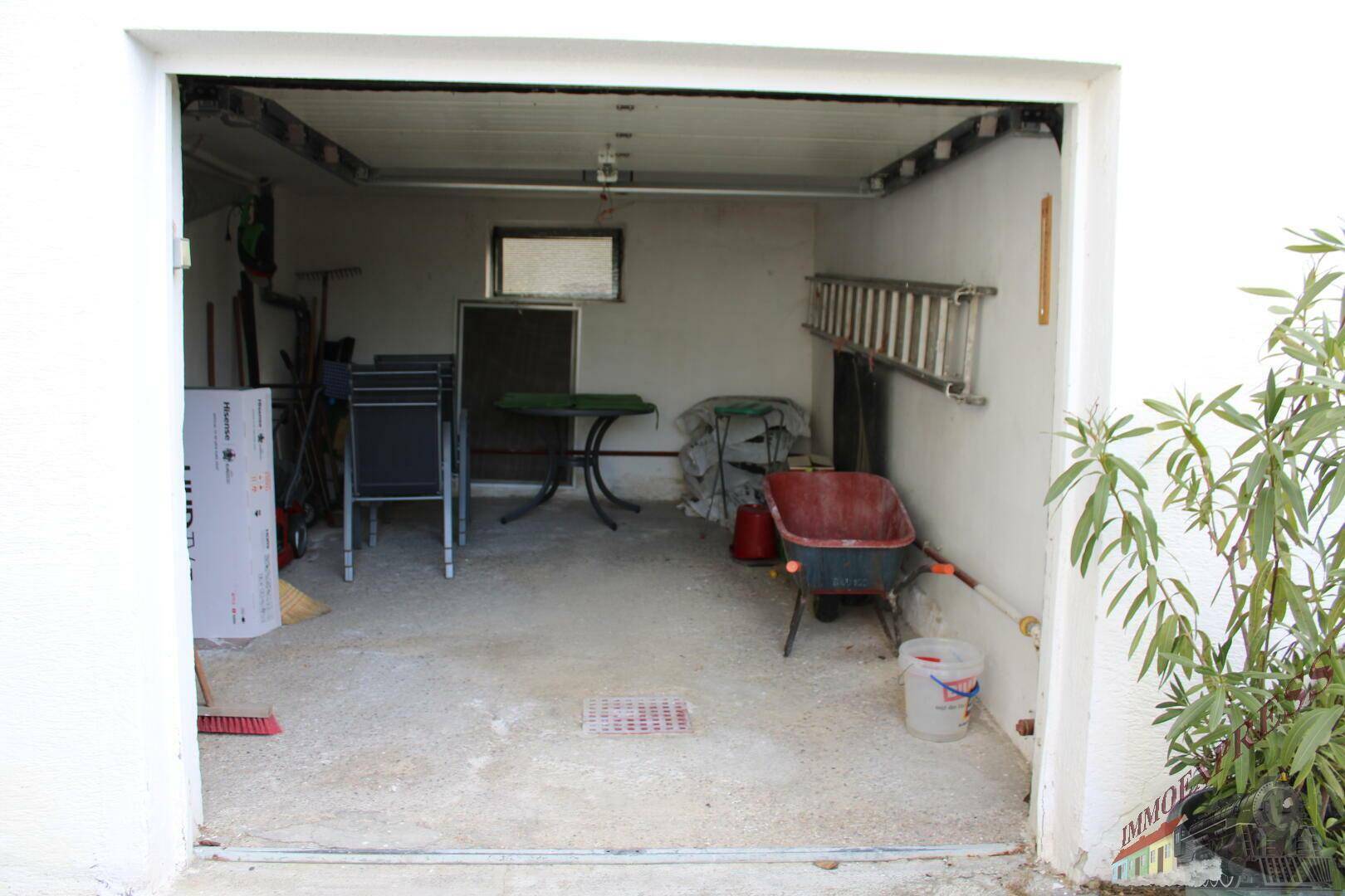 Geräumige Garage mit Betonboden und Stauraum für Gartengeräte, bietet viel Platz.