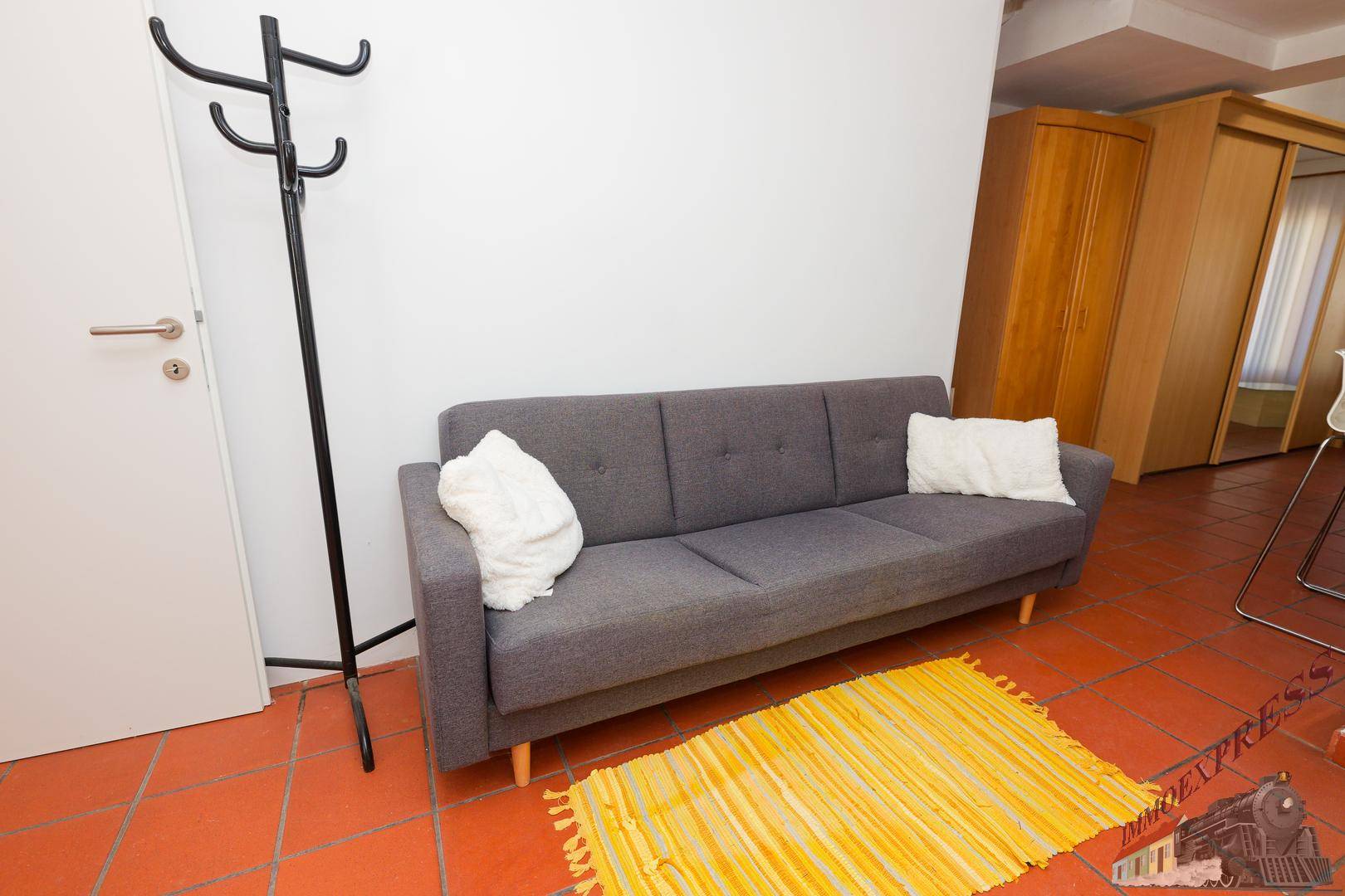 Eingangsbereich mit Garderobe, Sofa und Terrakottafliesen.