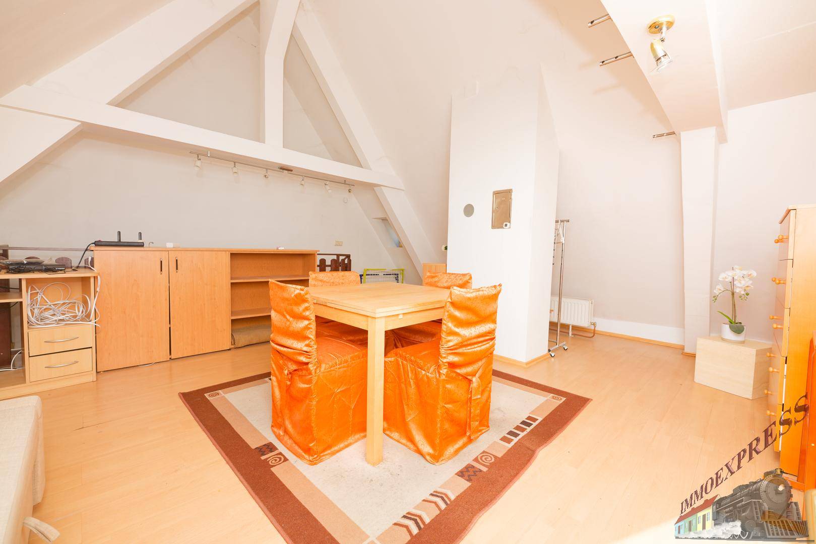 Geräumiger Dachboden mit sichtbaren Holzbalken, Essbereich und Stauraum.