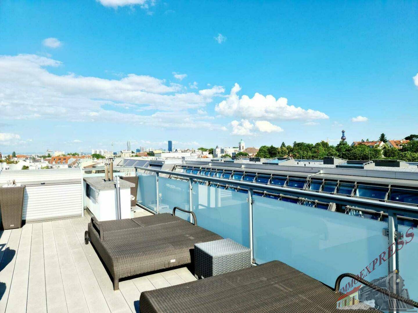 Weitläufige Dachterrasse mit Liegestühlen und Panoramablick über die Stadt unter blauem Himmel.