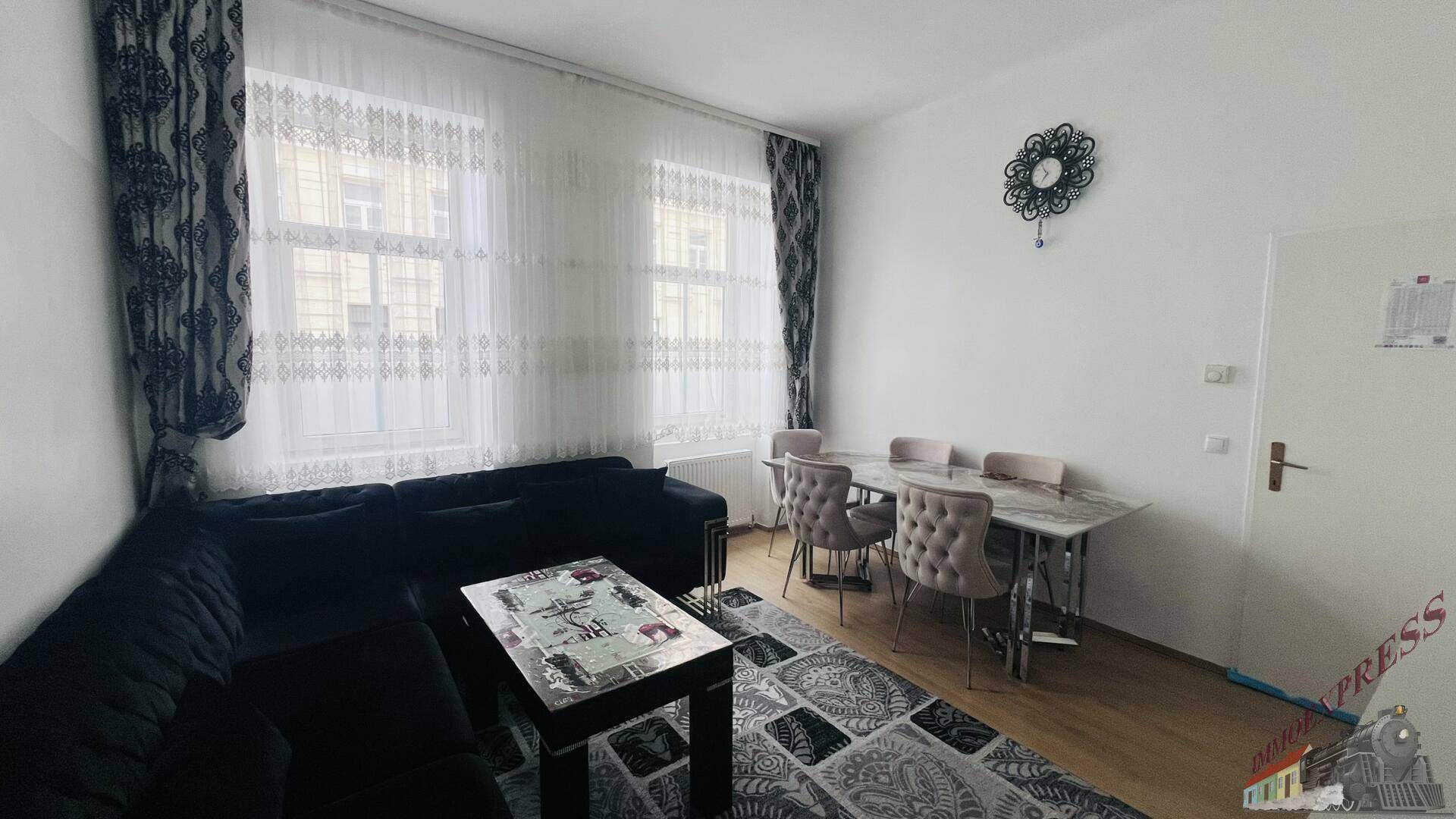 Geräumiger Wohn-Essbereich mit dunklem Ecksofa, Esstisch und großen Fenstern für viel Tageslicht.
