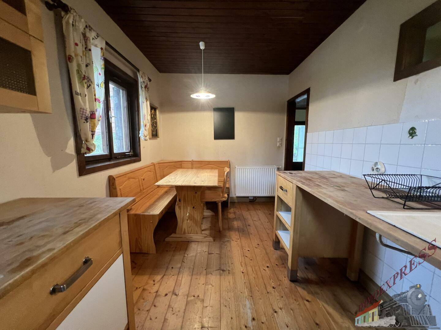 Gemütliche Küche mit Holzdielenboden, Holzdecke und einer traditionellen Eckbank mit Esstisch.